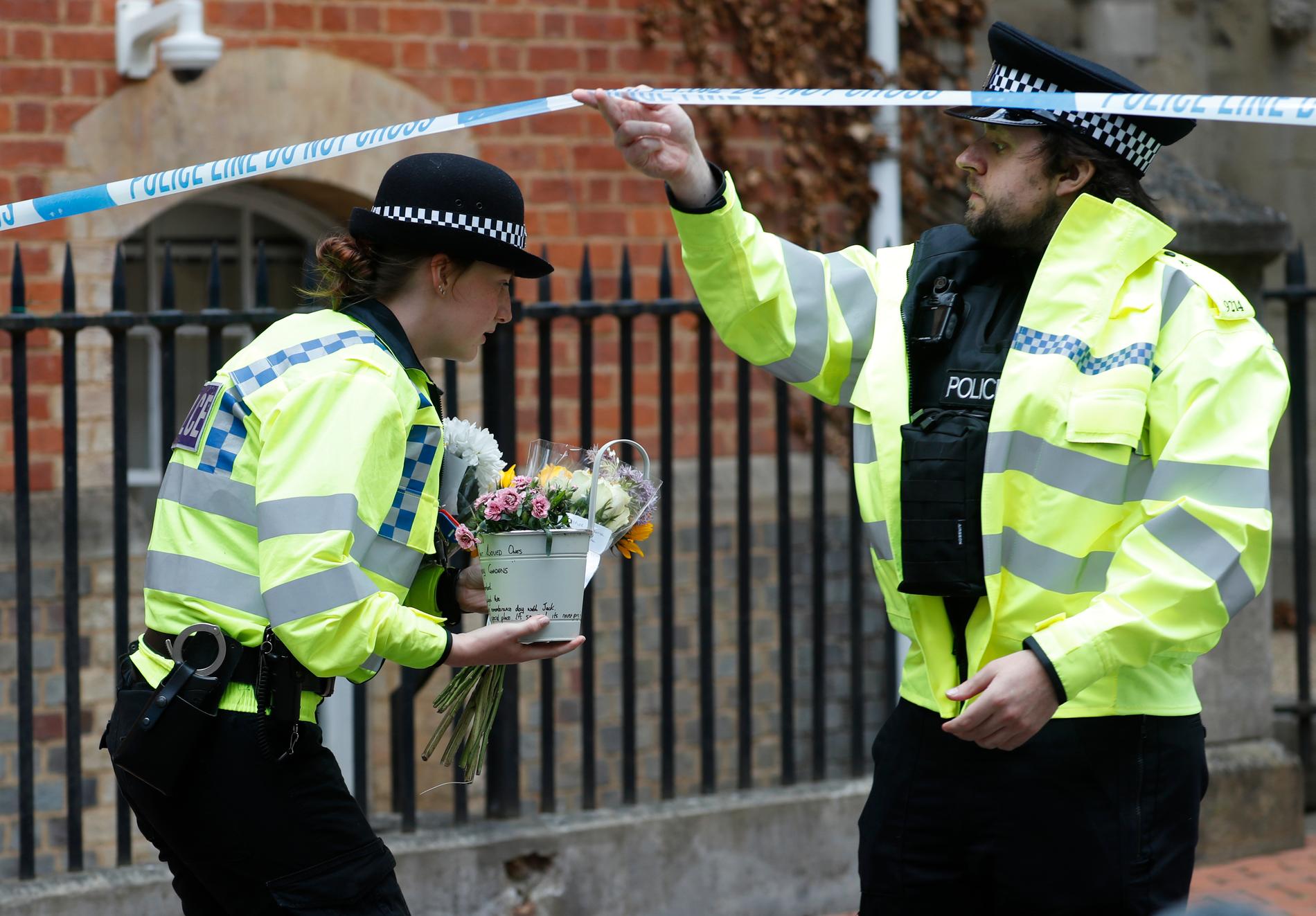 Poliser hämtar blommor som lämnats efter knivdådet i Reading i lördags.