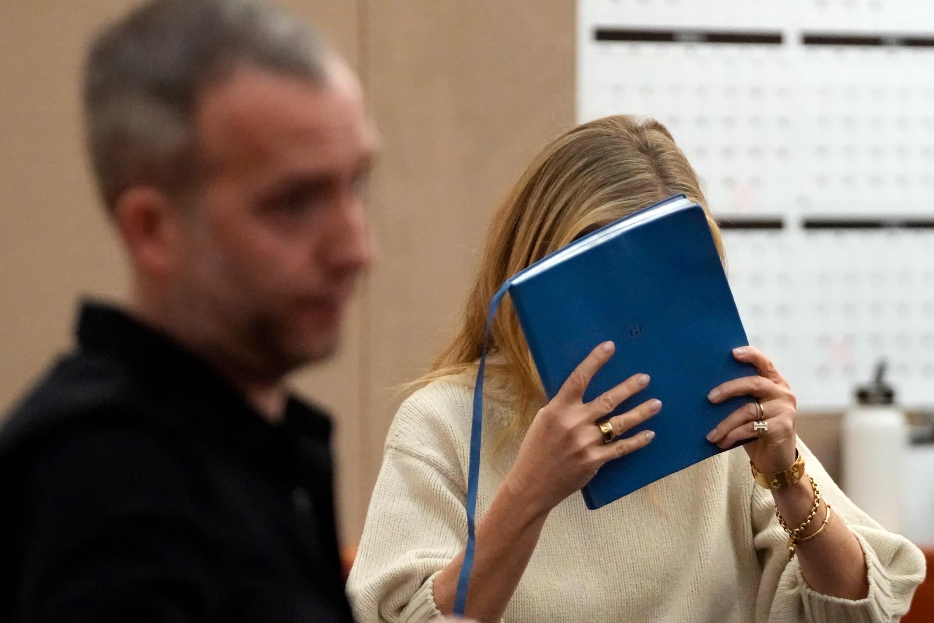 Gwyneth Paltrow försöker gömma sig bakom ett skrivblock på vägen ut från rättegången. 