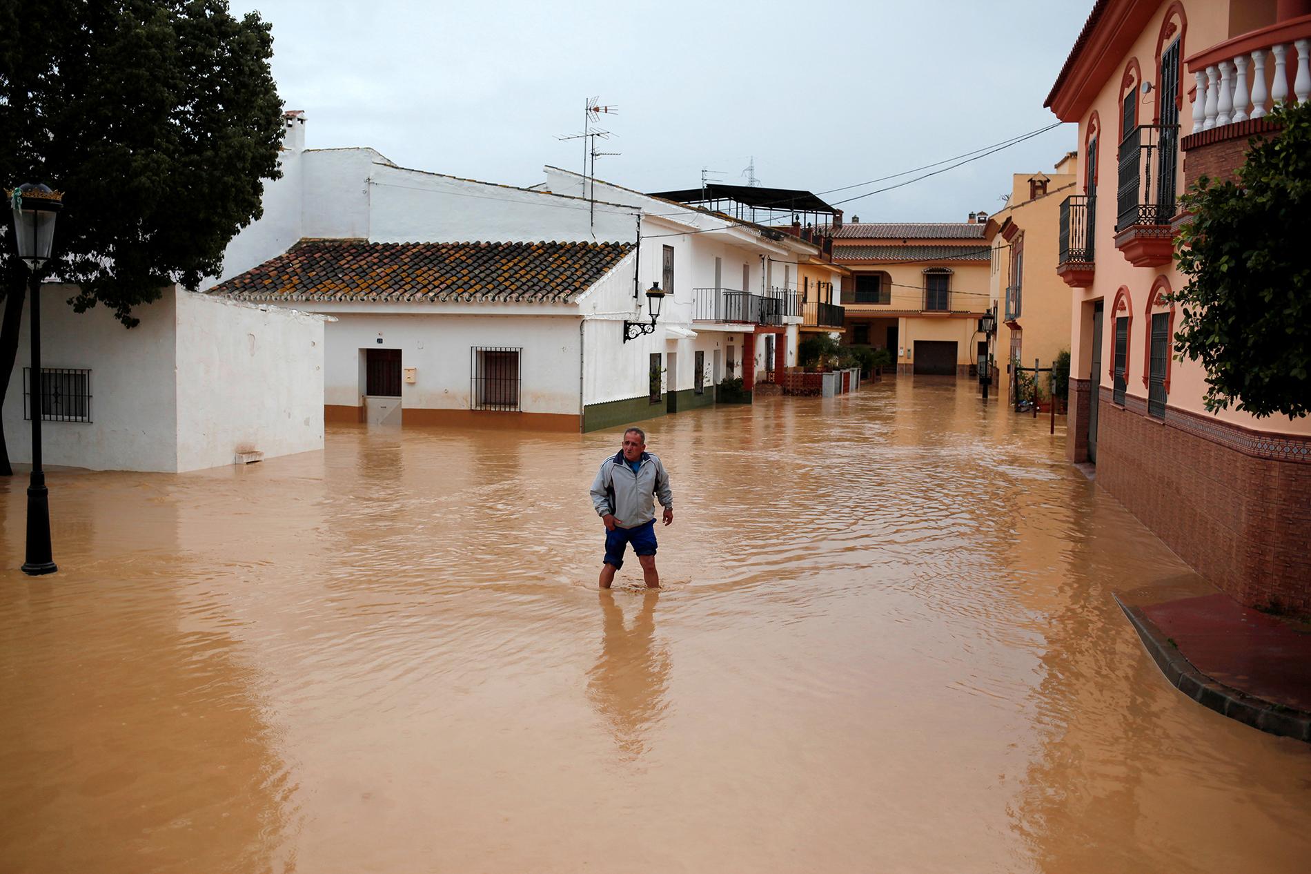 En man som övergivit sitt hem vadar genom de översvämmade gatorna i Cartama, nära Malaga.