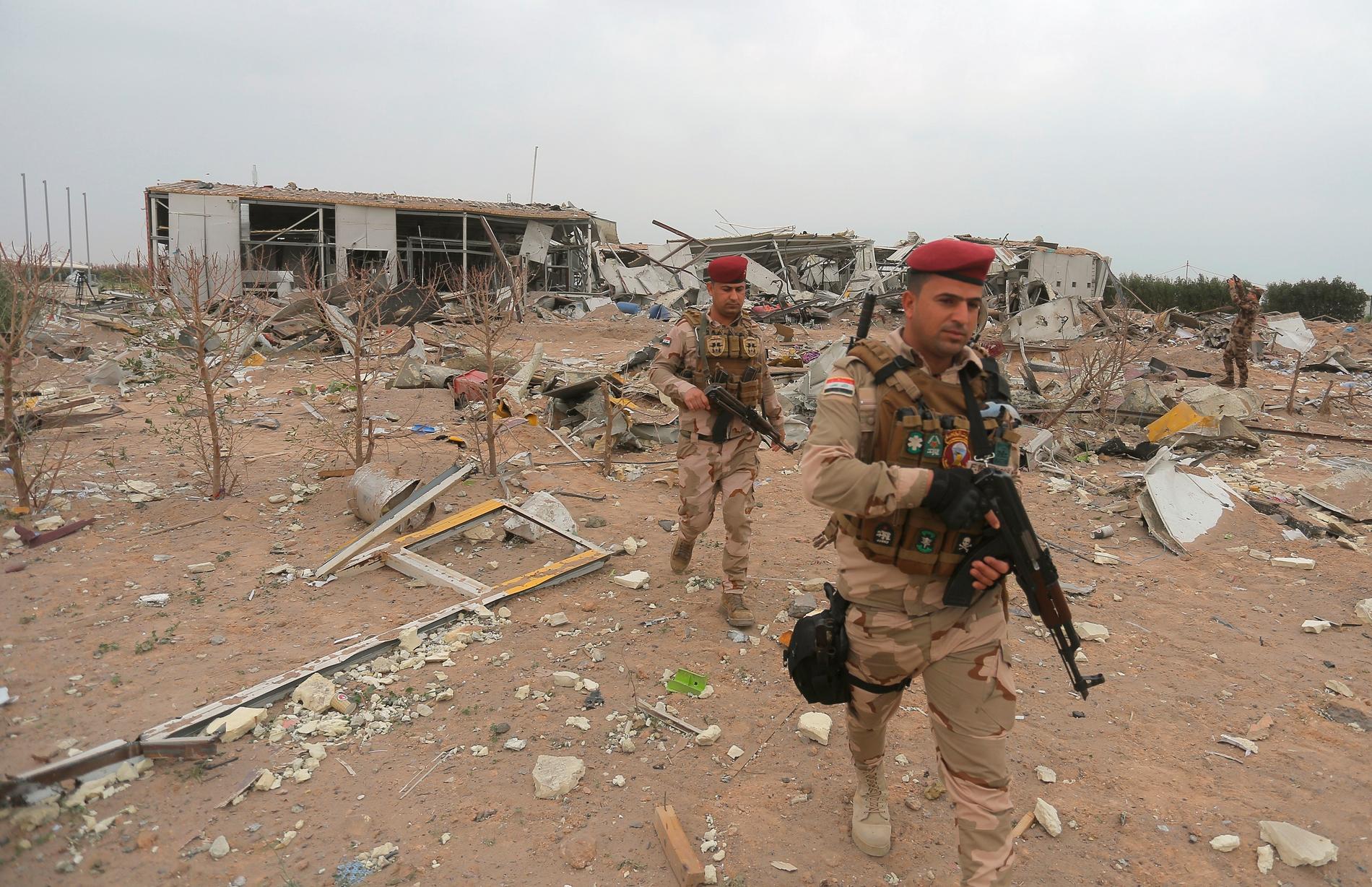 Irakiska soldater inspekterar en flygplats som förstördes i en amerikansk vedergällningsattack efter angreppet på Tajibasen den 11 mars.