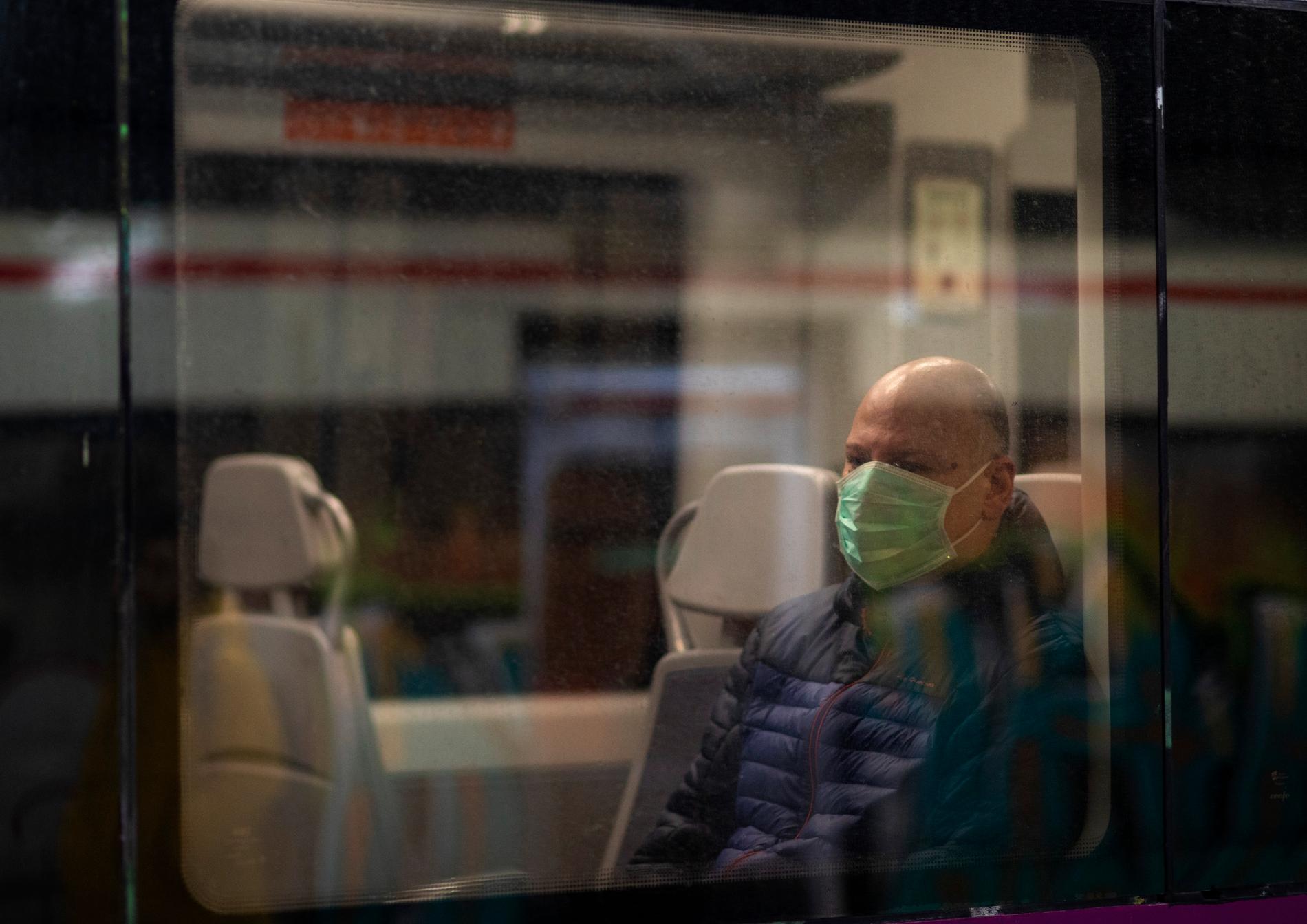 En man med mask för ansiktet åker tåg i Barcelona.