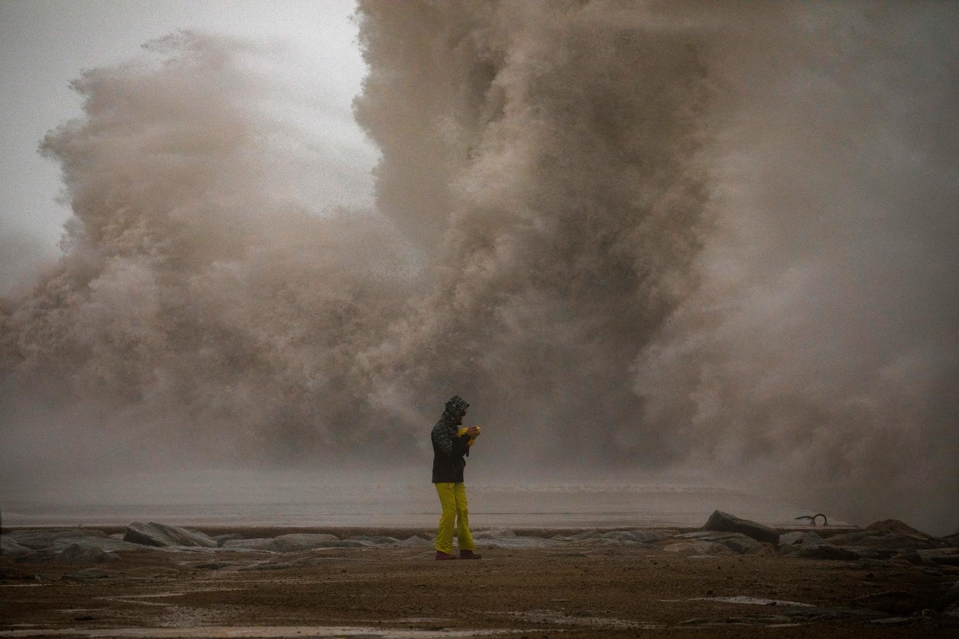 En kvinna i Barcelona fotograferar ett stormigt Medelhav. Bild tagen den 21 januari.