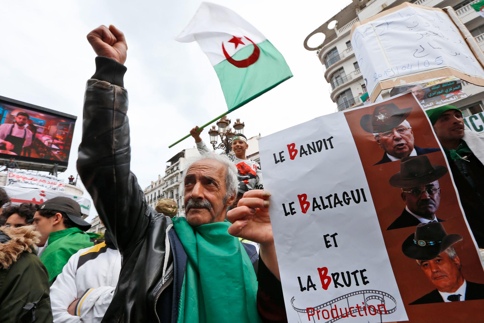 En man demonstrerar mot den styrande så kallade B-trion under en marsch i Algeriets huvudstad Alger i april. Han håller upp ett plakat med franska ord som börjar på B, som betyder ungefär banditer, odjur och maktens hantlangare.