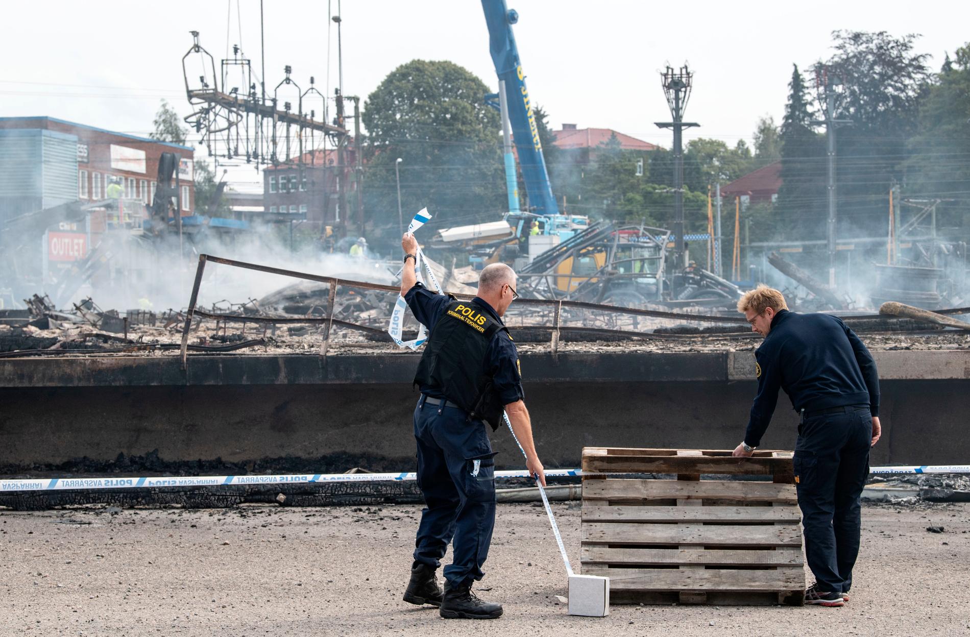 Polisens kriminaltekniker spärrar av medan de skadade kontaktledningarna och signalsystemkablarna demonteras och röjs undan strax norr om Hässleholm C efter en kraftig brand i augusti i en industribyggnad. Arkivbild.