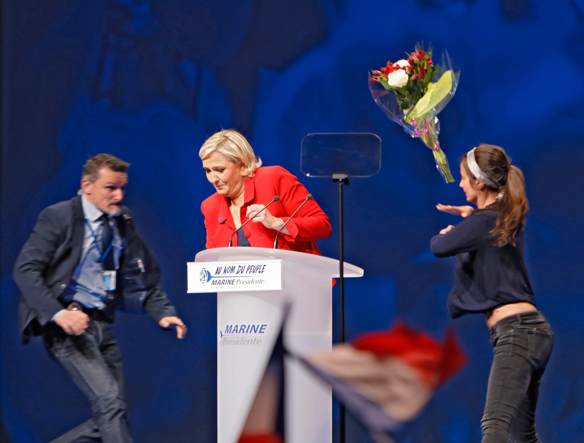 Marine Le Pen överfölls av en "Femen kvinna" som kastade blommor och försökte blotta sig. 