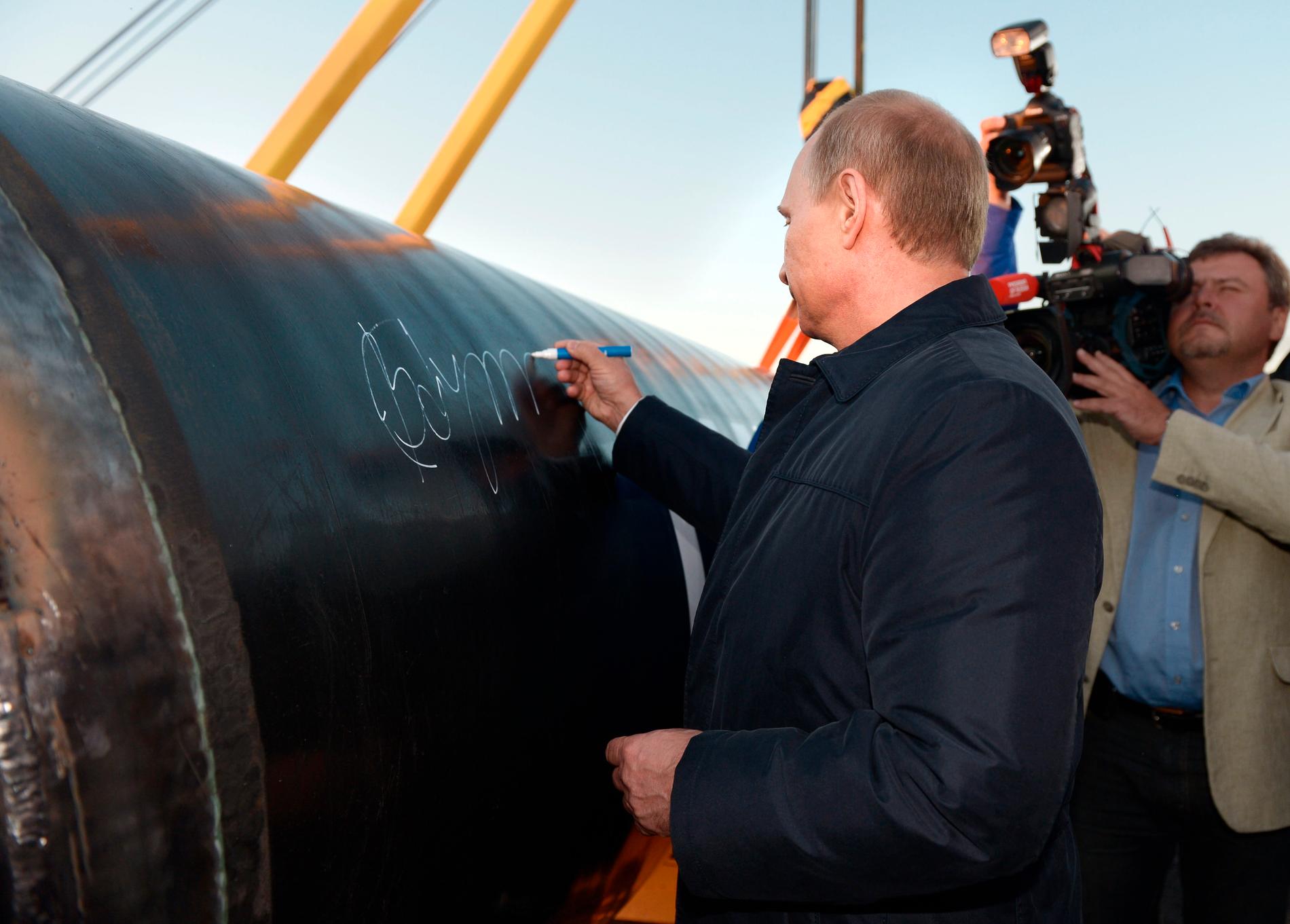 Vladimir Putin sätter sin autograf på pipelinen som ska föra gas från Ryssland till Kina.