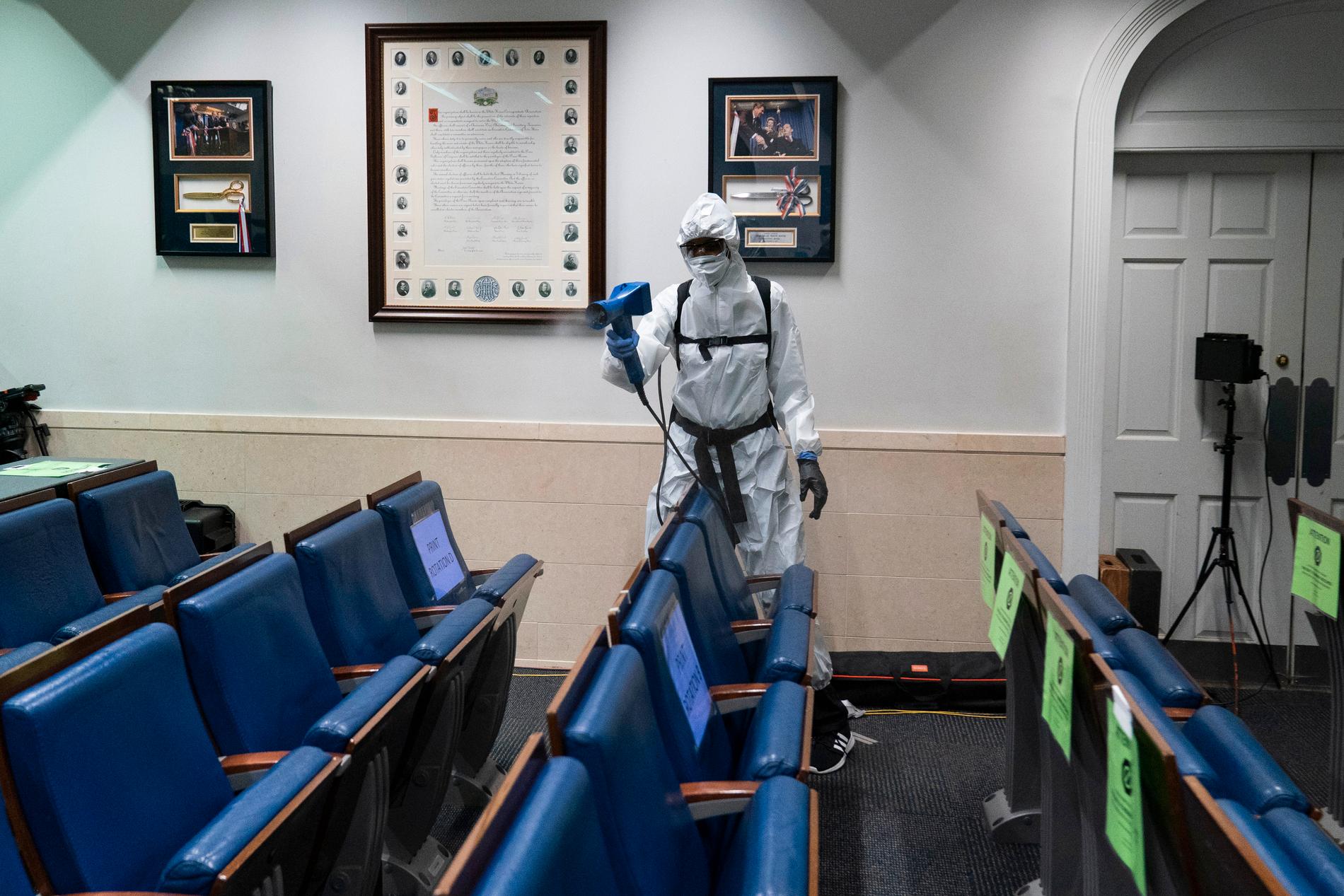 Städare i skyddskläder sprutar desinfektionsmedel i Vita husets pressrum.