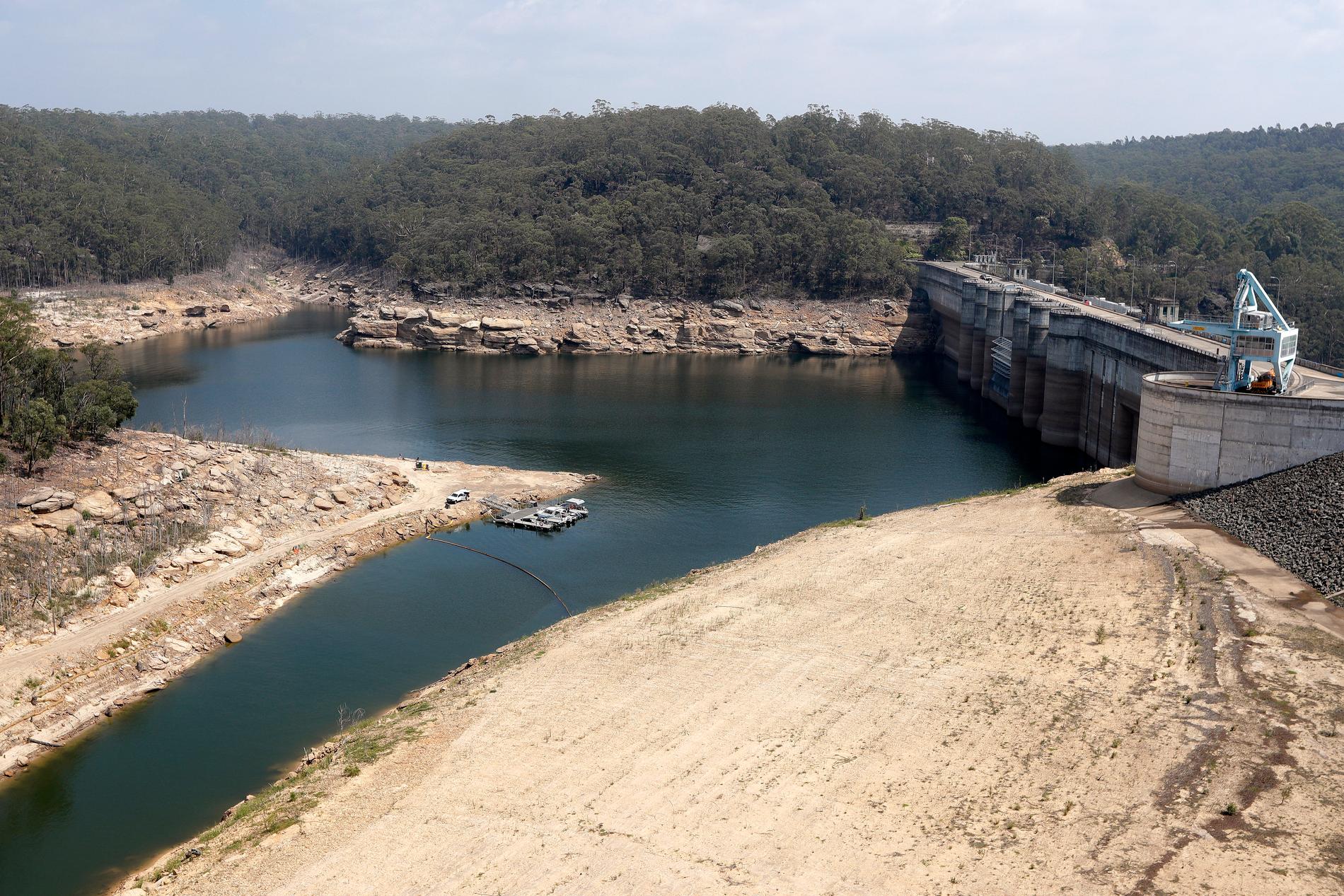En flytande barriär har placerats i Warragamba-dammen för att skydda mot aska, som kan spolas med när regnet till slut faller över de branddrabbade områdena. Vattennivån i dammen är låg till följd av torka.