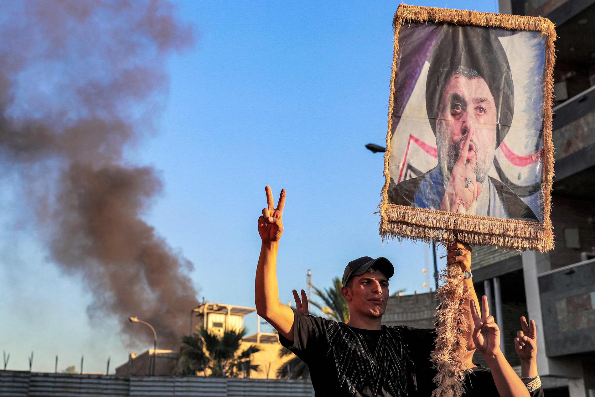 Supportrar håller upp en bild av  shiitiske milisledaren Moqtada al-Sadr framför den brinnande svenska ambassaden i Bagdad. 