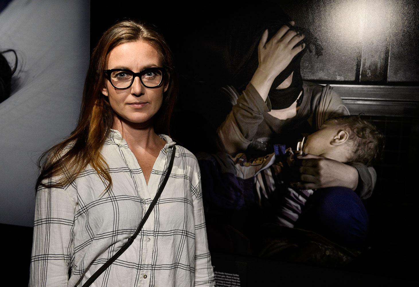 Journalisten Sanna Lundell framför sin favoritbild på utställningen: den av ettårige Sham och hans mamma vid järngrinden på gränsen mellan Serbien och Ungern.