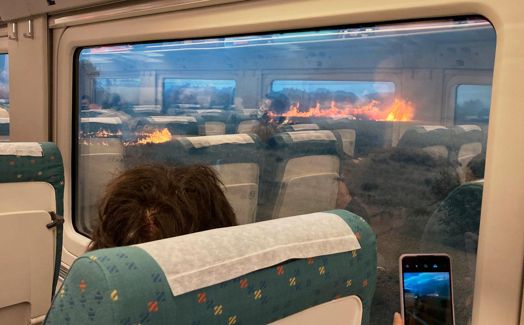 Passagerare i spanska Zamora filmar och fotograferar branden som omger det stillastående tåget.