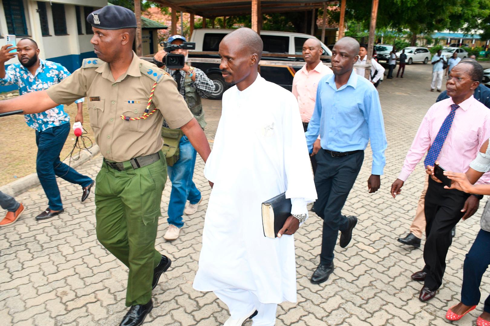 Ezekiel Odero, en av två åtalade sektledare, håller i en bibel medan han eskorteras av polis i Mombasa, Kenya.