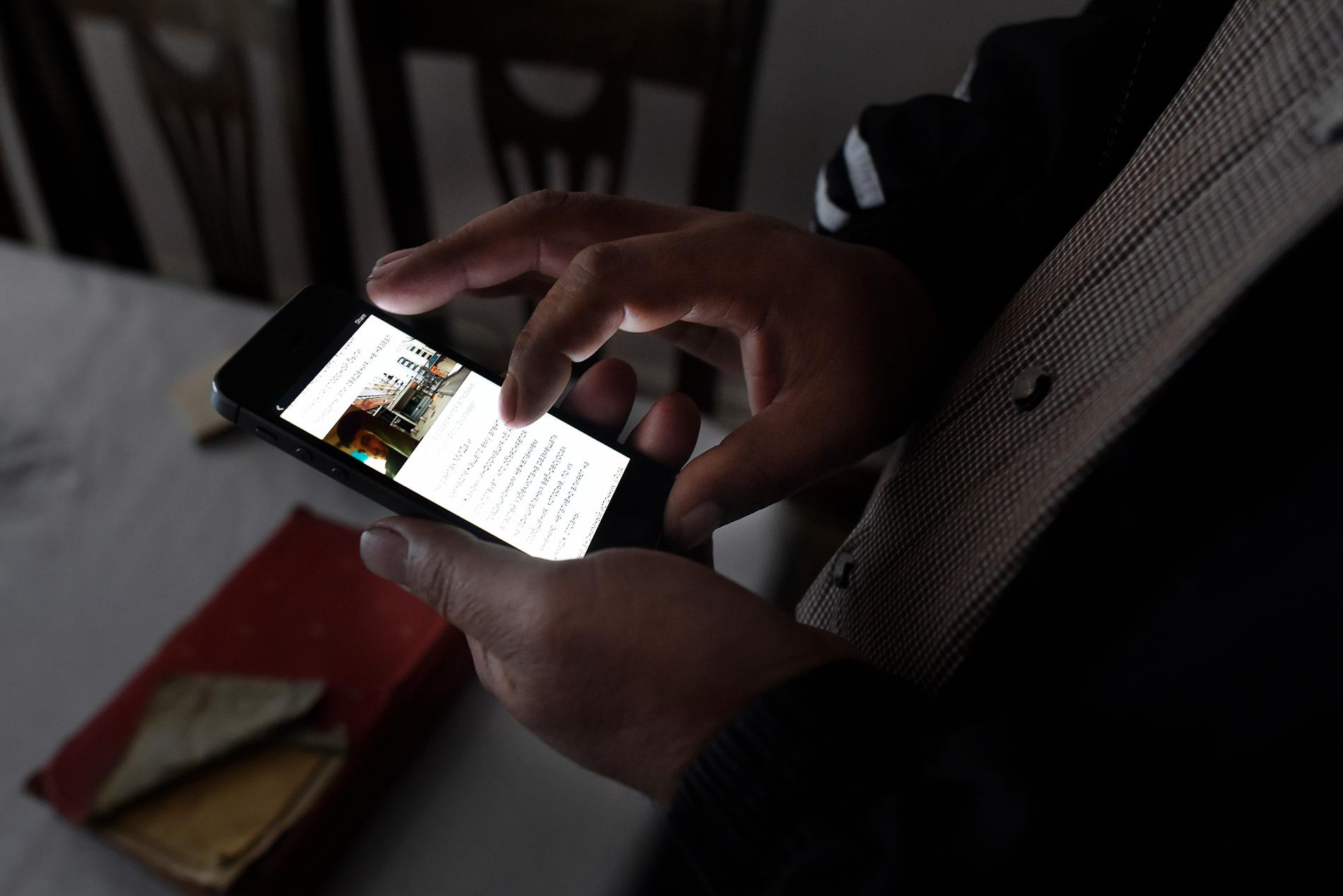 Olim Akilov får låna Aftonbladets utsändas telefon för att läsa om broderns terrordåd.