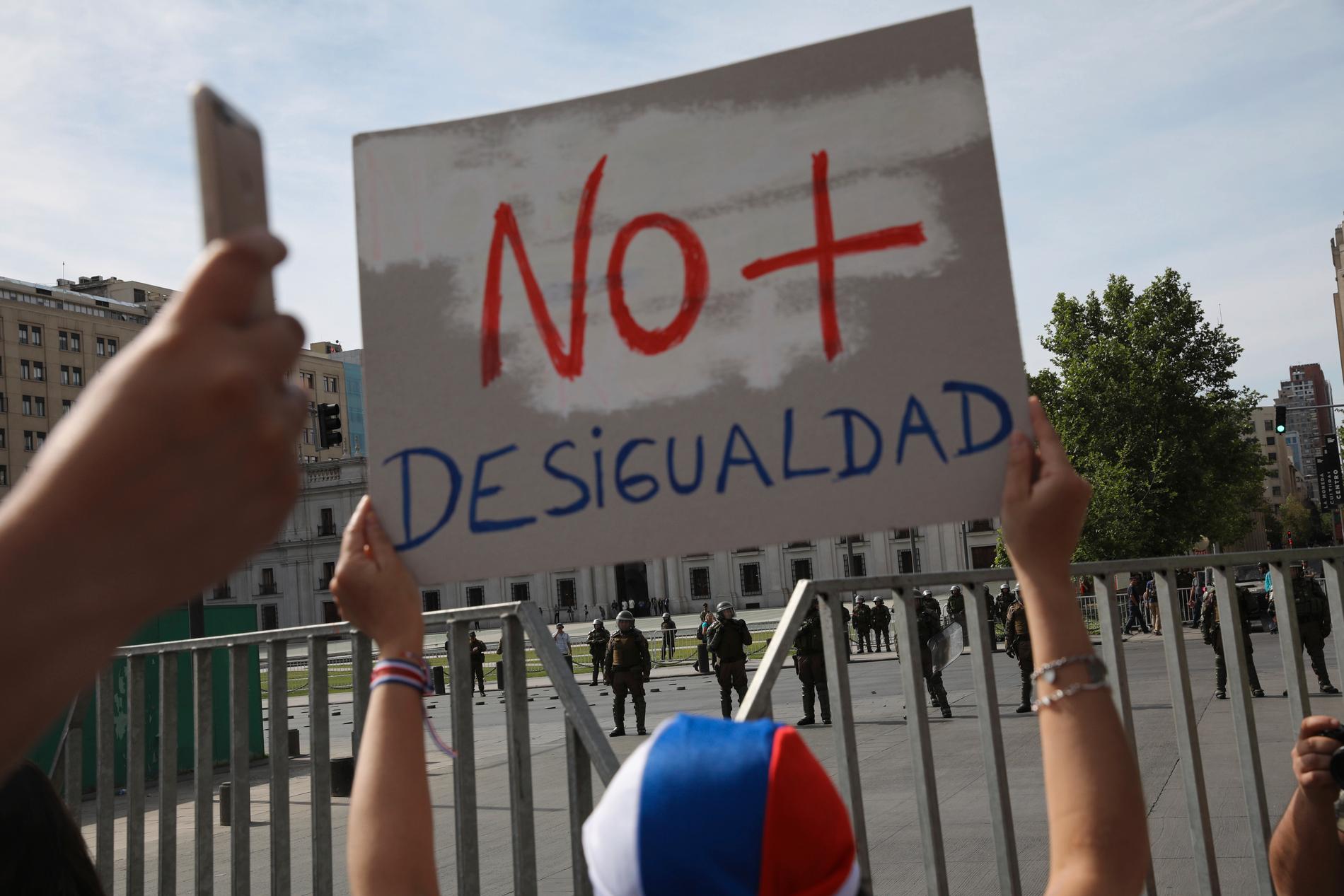En demonstrant håller upp en skylt med texten "Ingen mer ojämlikhet" under protester utanför presidentpalatset La Moneda i Chiles huvudstad Santiago i lördags.