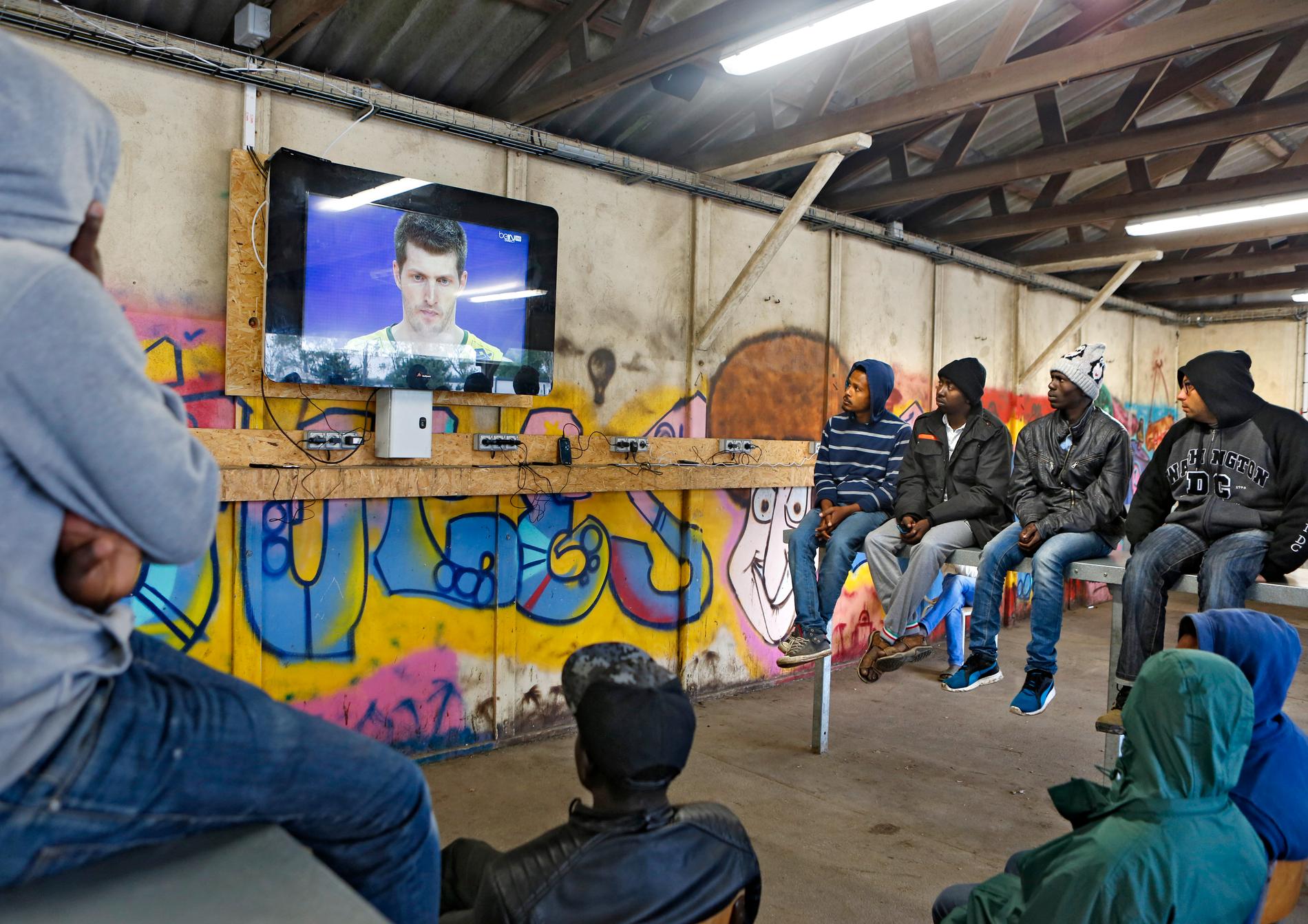 I flyktinglägret i Calais samlas människor framför en tv för att följa fotbolls-EM och andra sportevenemang. ”Det är många flyktingar här och tittar. Det ger dem glädje och något att göra, det finns inte så mycket­ annat att slå ihjäl tiden med här”, säger Philippe Glavieaux, en ­
av de ansvariga på centrat.