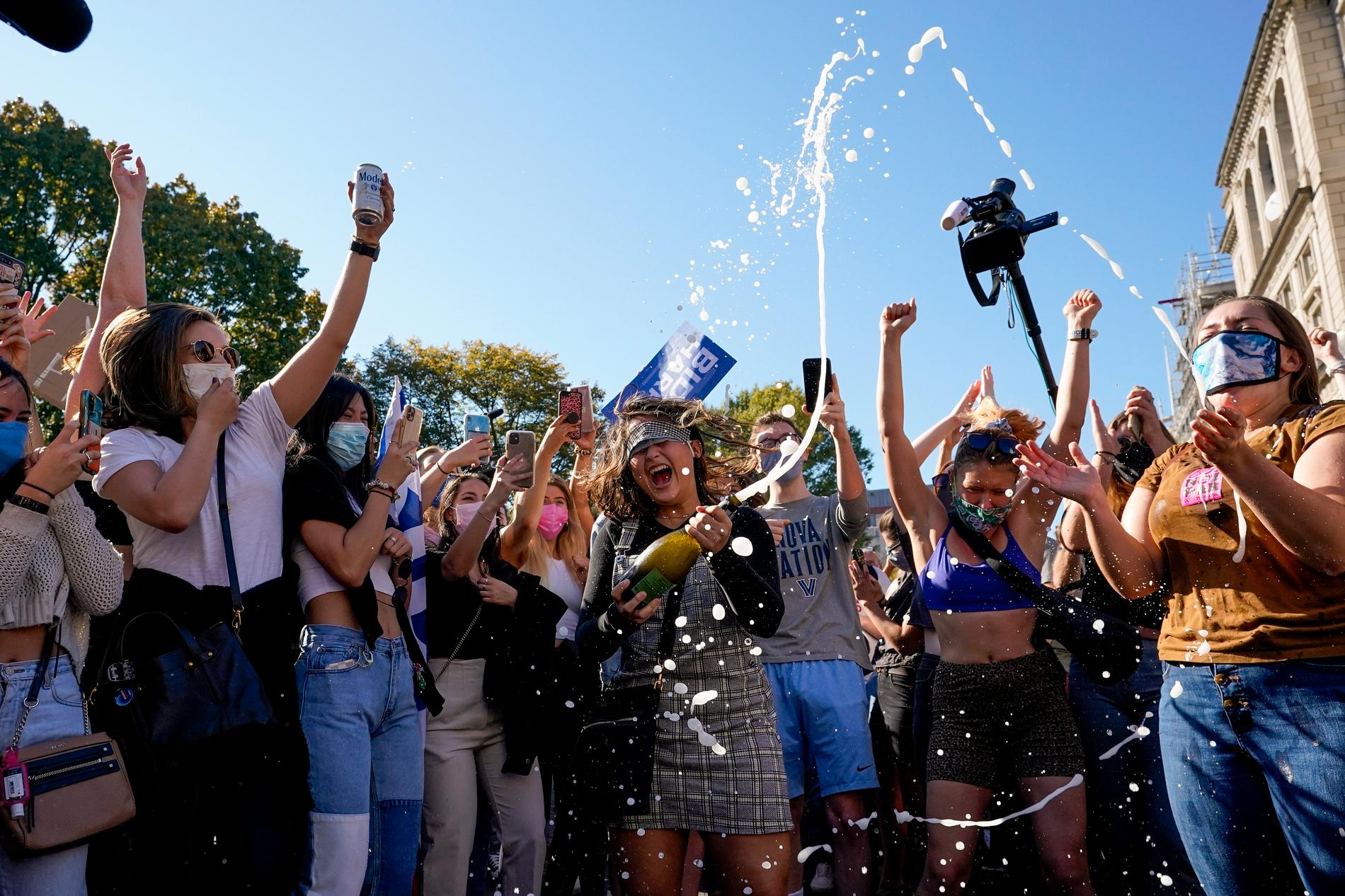 Amanda Madden sprutar champagne när en samling glada människor firar beskedet från Pennsylvania på Black Lives Matter Plazai Washington.