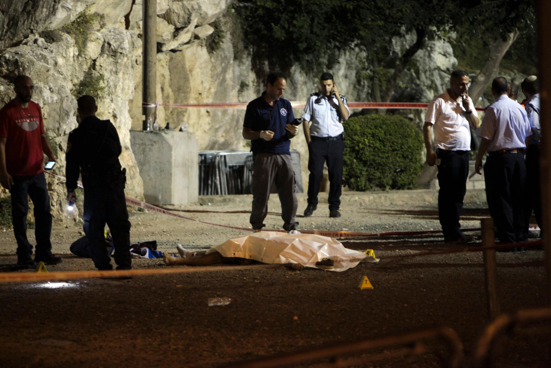 Israeliska poliser invid en av de tre angripare som sköts ihjäl utanför Jerusalems gamla stad.