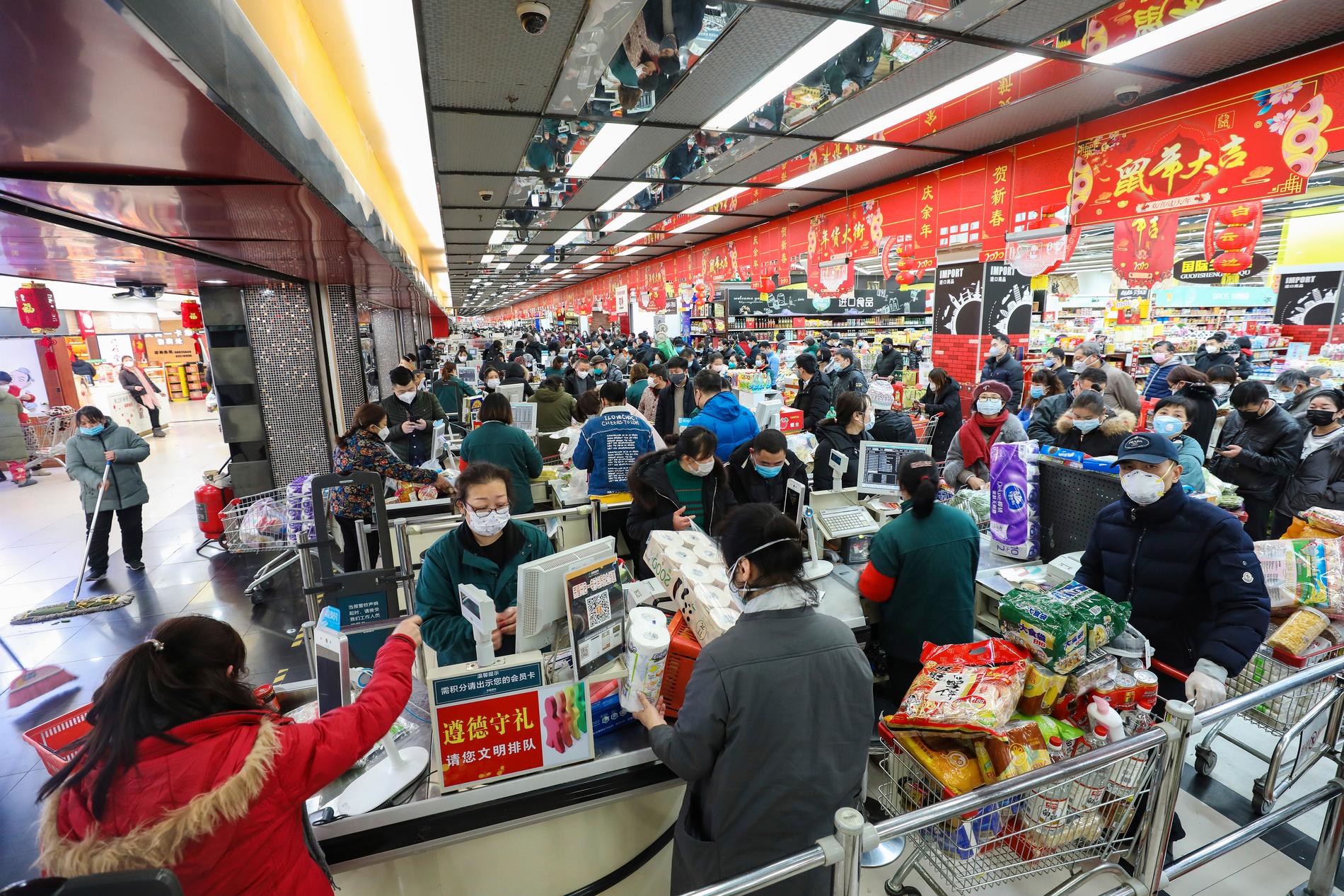 Invånare i Wuhan handlar mat med ansiktsmasker på.