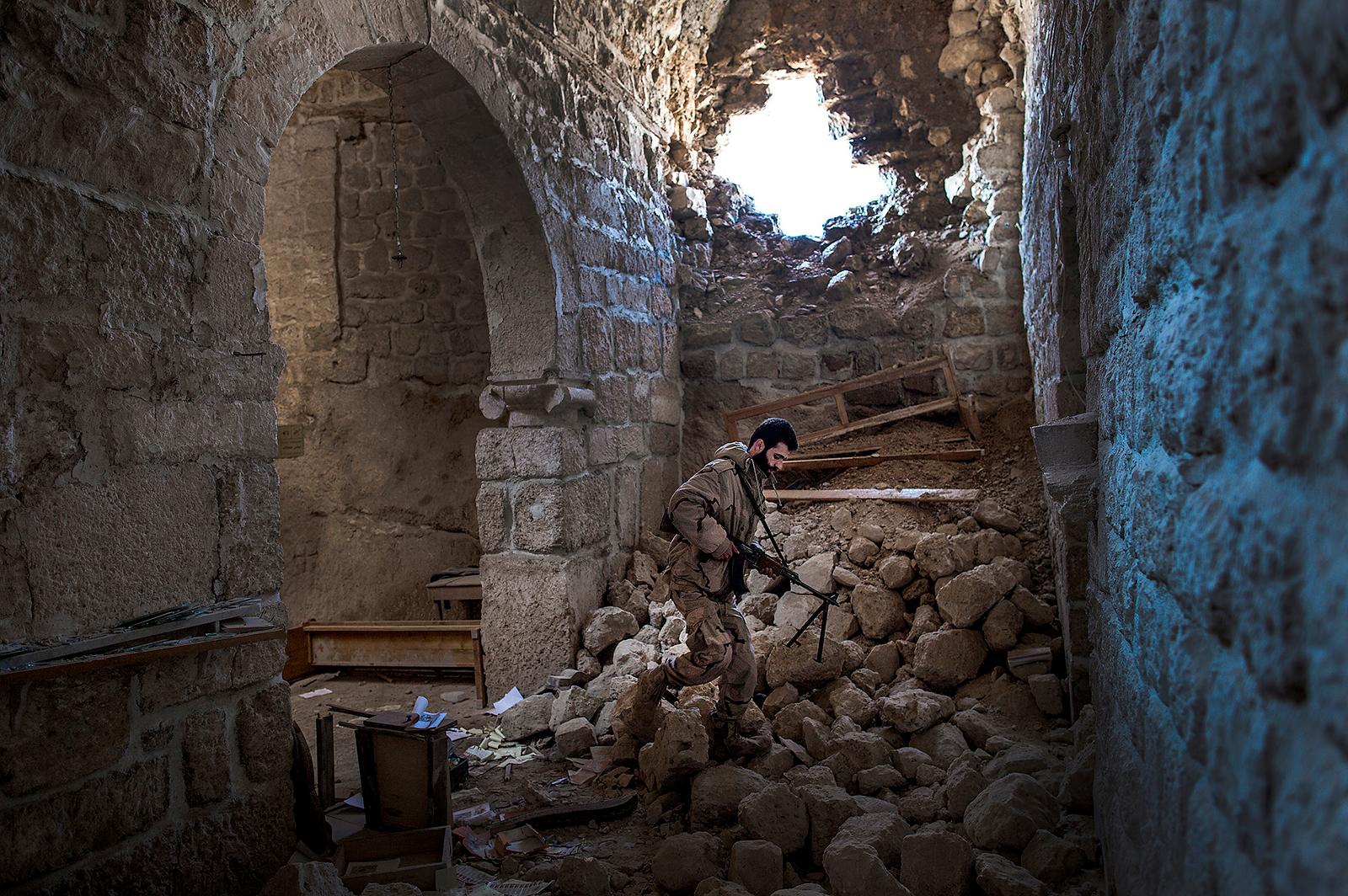 guds hus i ruiner Amjad Hamad, 26, är ledare för en pluton inom FSA, Free Syrian Army. Här går han i ruinerna efter kyrkan i Maaloula som blivit sönderbombad av regimen.
