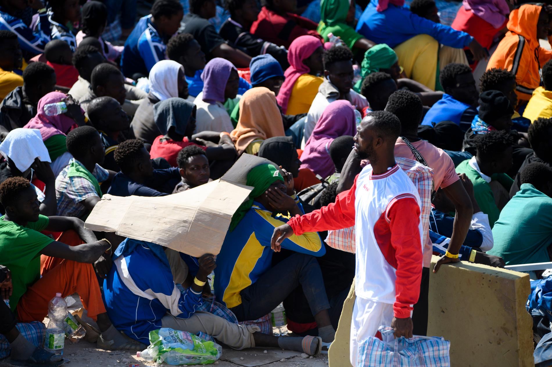 Migranter utanför Röda Korsets mottagningscenter på den italienska ön Lampedusa, en så kallad "hot spot" där ingen är tänkt att stanna mer än tre dygn. Bilden togs i torsdags, dagen efter att över 6 800 migranter anlänt till ön.