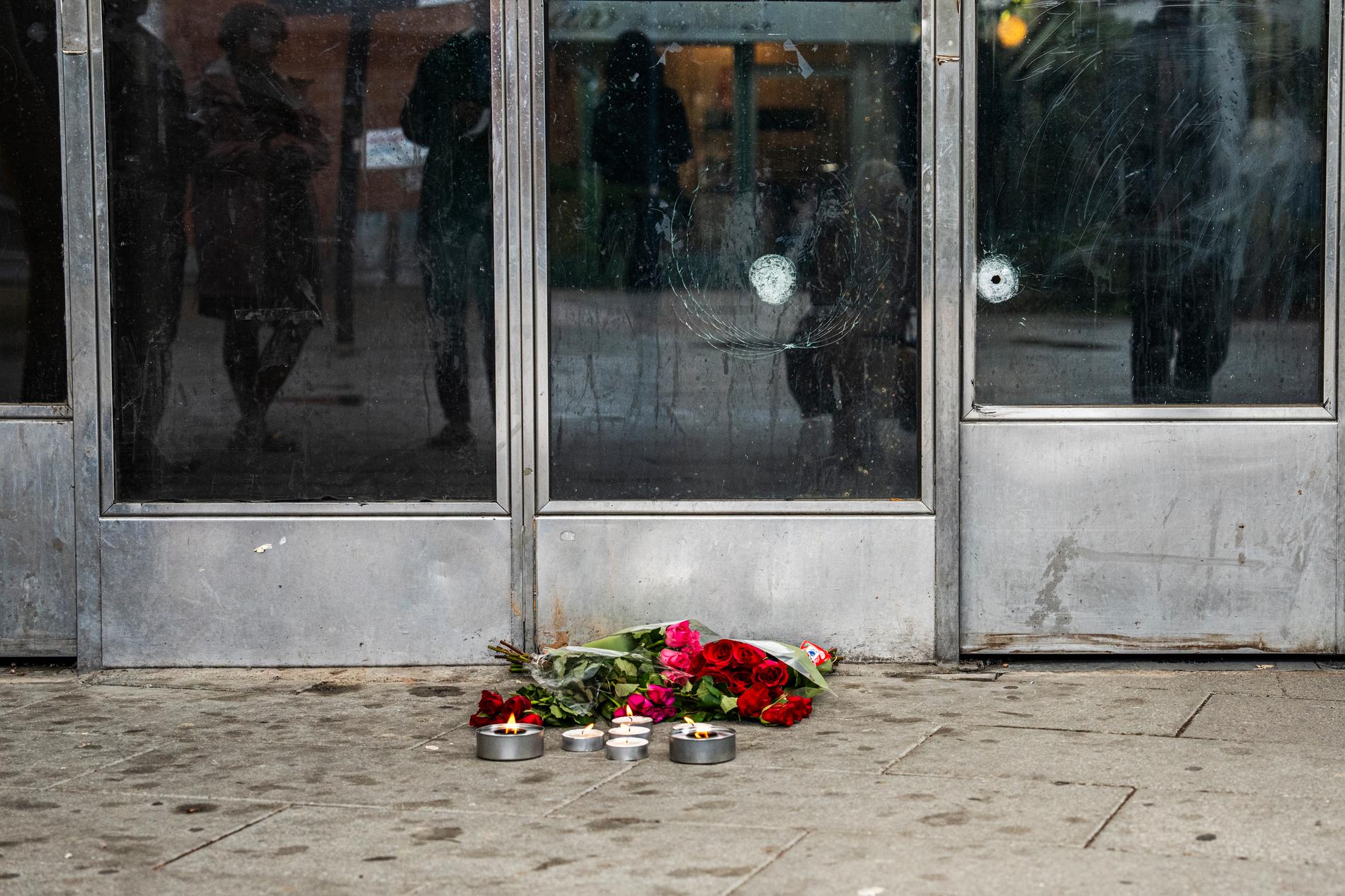 Blommor och ljus på platsen där en man i 20-årsåldern sköts till döds. 
