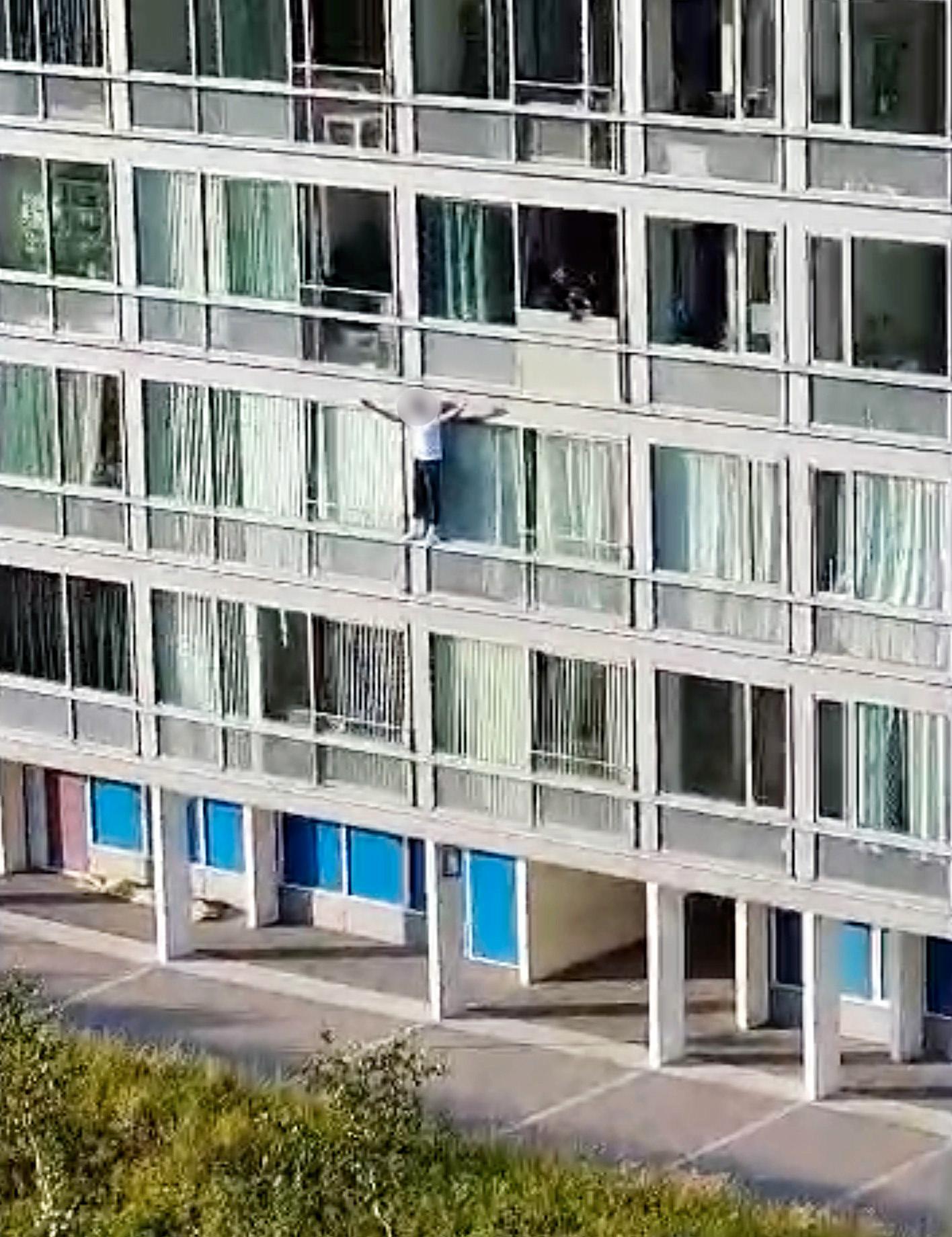 Han filmades hängandes från balkongen. Senare kunde han gripas av polis. 