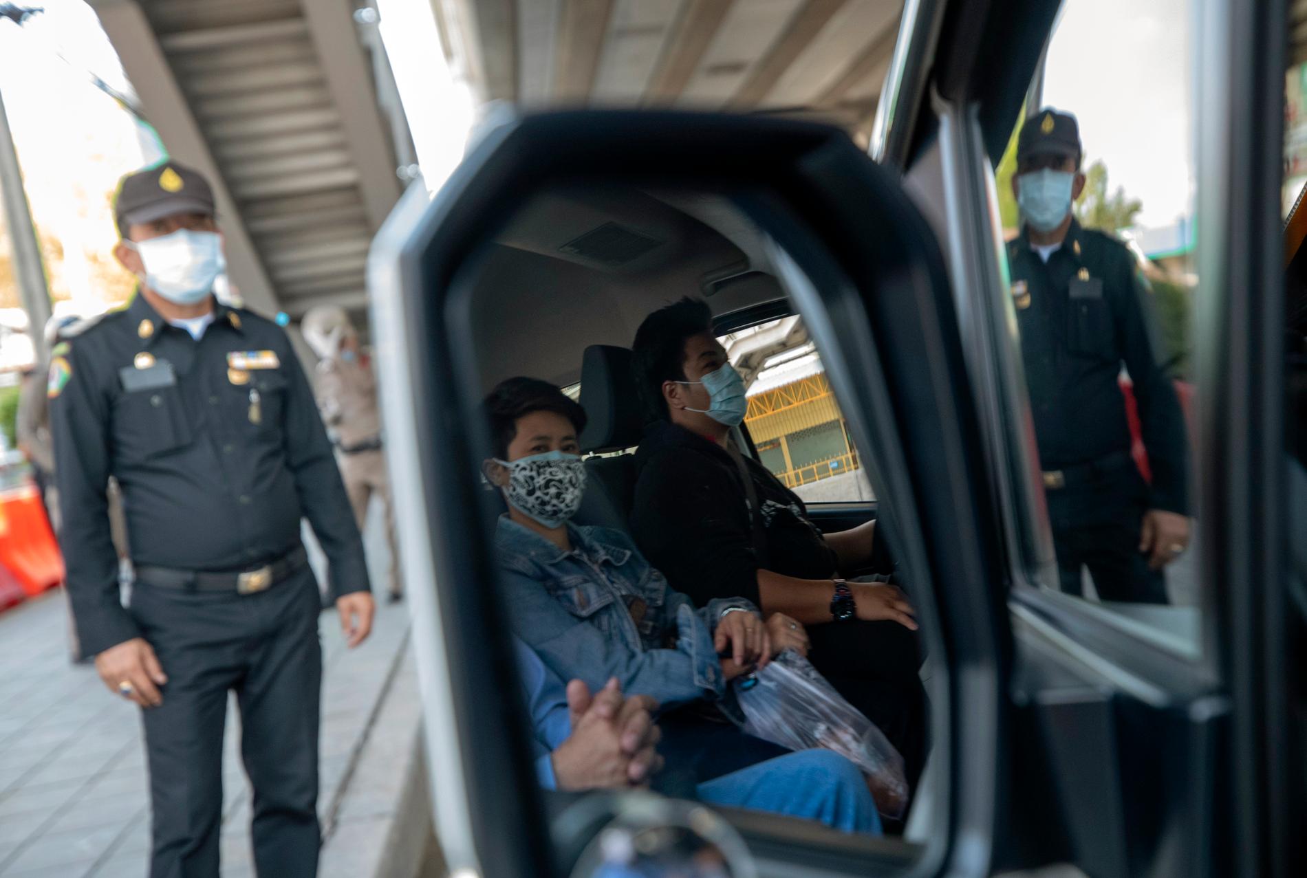 En polis stannar ett fordon i Bangkok för att kontrollera att förare och passagerare inte har feber.