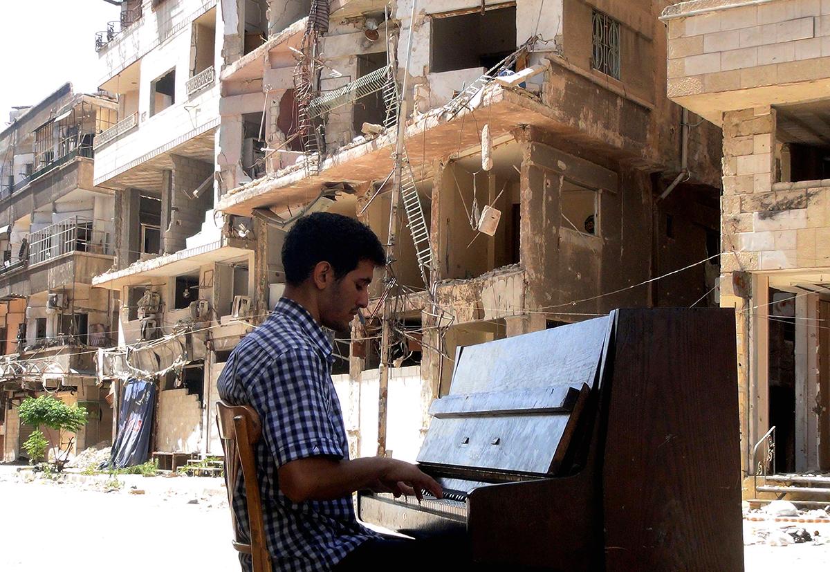 Damaskus, Syrien: Ayham al-Ahmed spelar piano på en sönderbombad gata i flyktinglägret Yarmuk i södra Damaskus. Utanför bild står barn från lägret och sjunger.