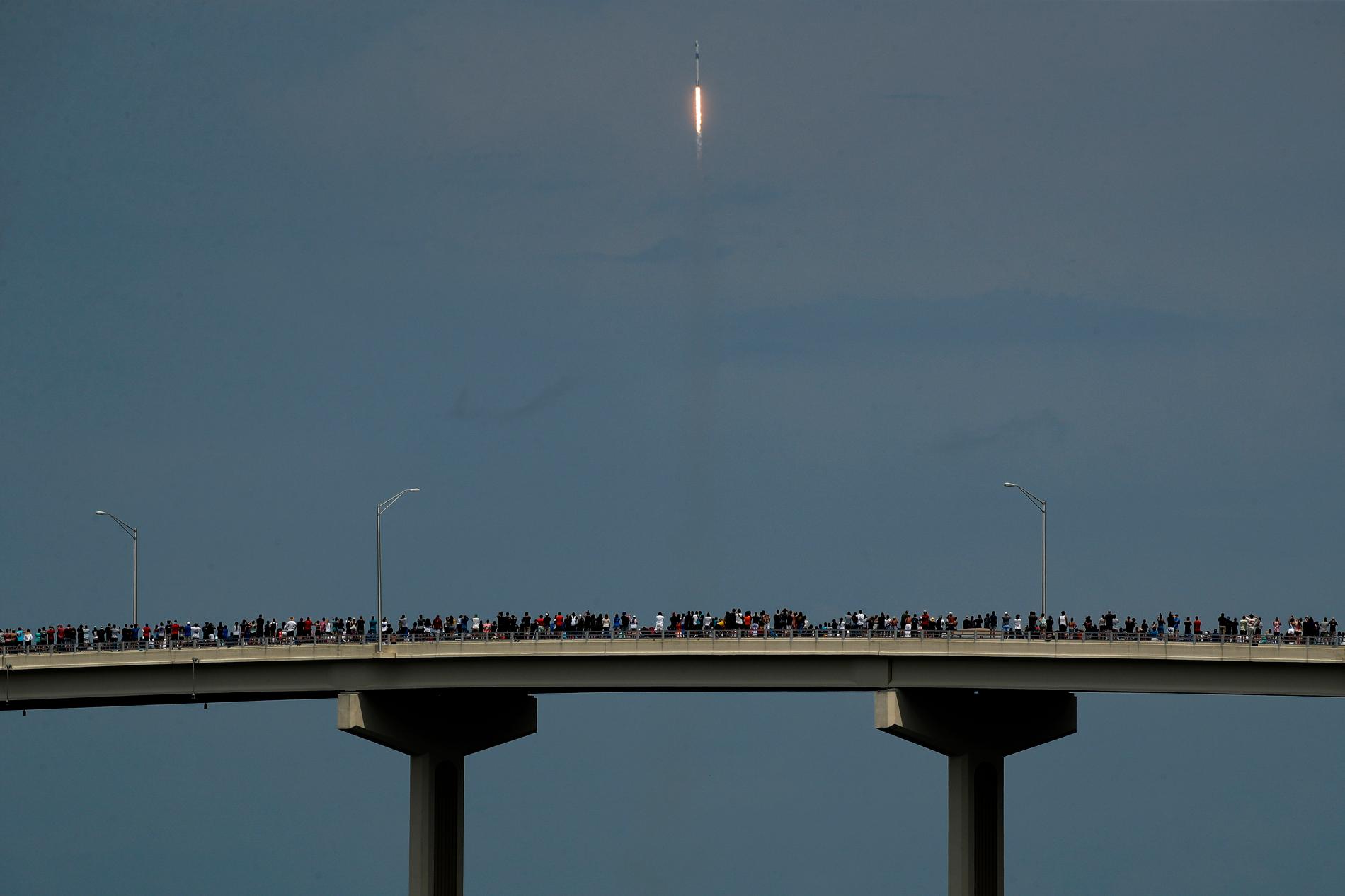 Raketuppskjutningar är ett folknöje i Florida, även i covidtider. Här beundrar samlade åskådare den stigande Falcon 9-raketen från en bro i Titusville.