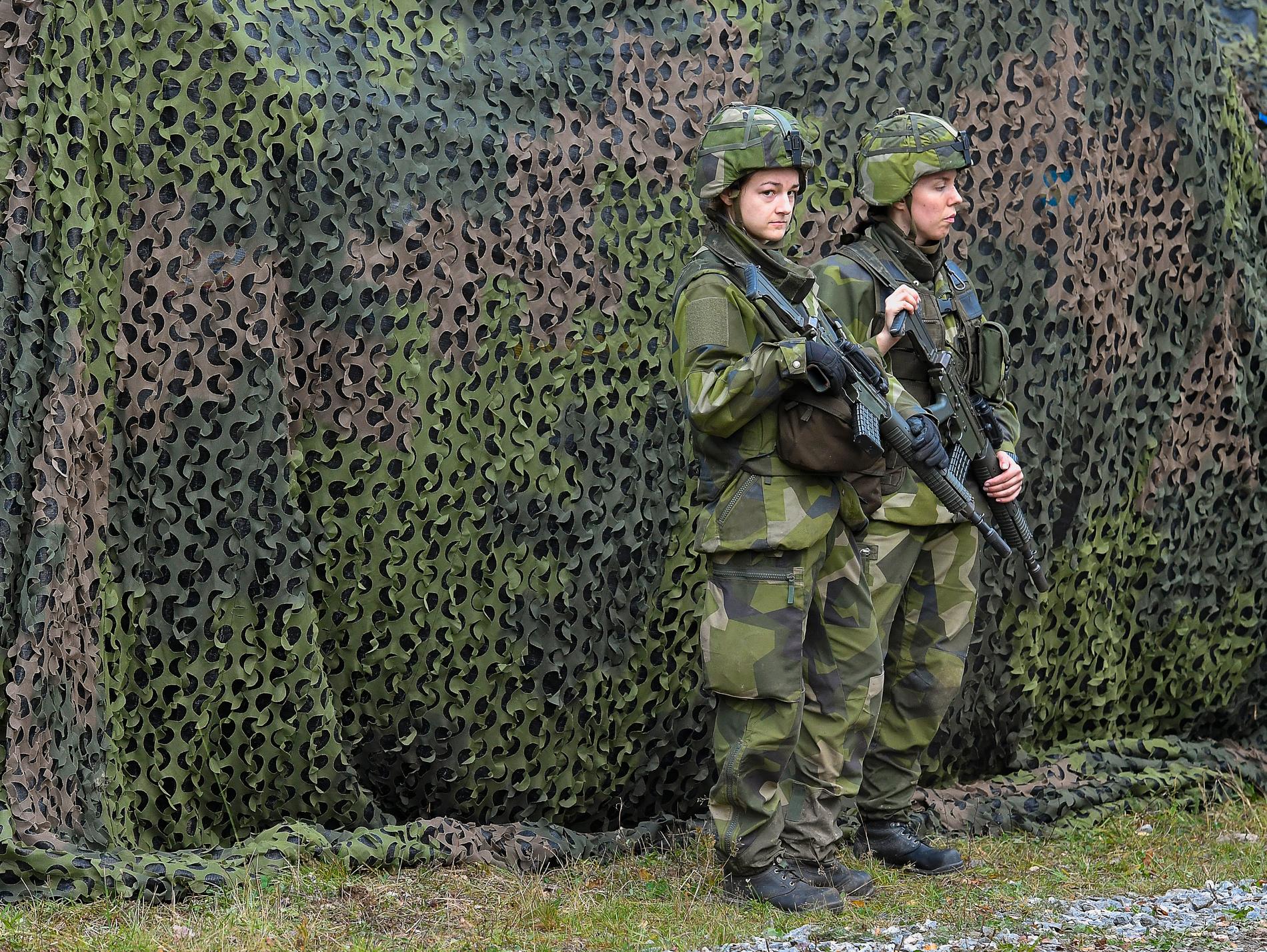 Militärfordon med skyddsnät vaktas av två soldater under försvarsövningen Aurora 17. Arkivbild.