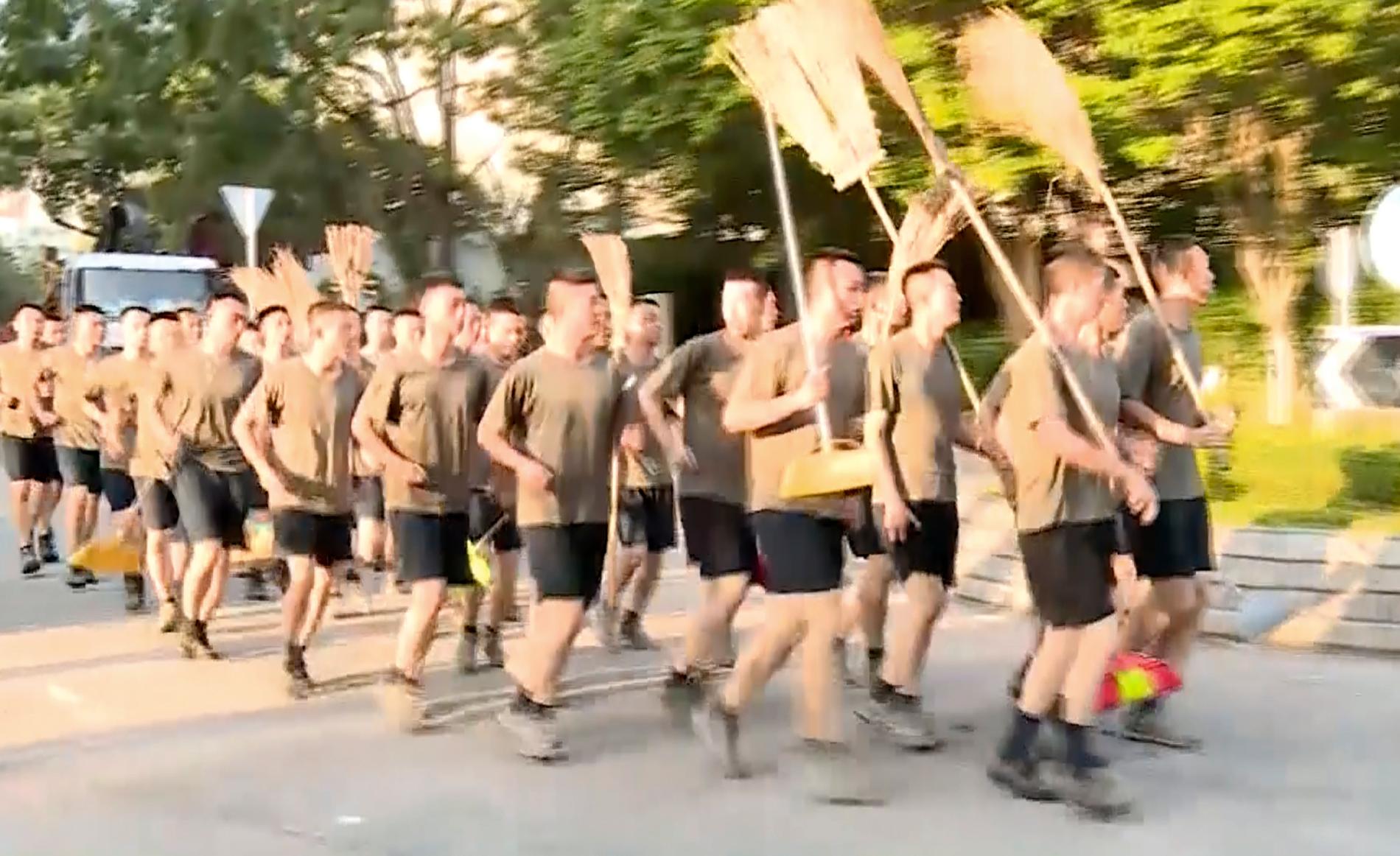 En bild från en videoupptagning visar kinesiska soldater med kvastar som anländer för att städa gator i Hongkong på lördagen.