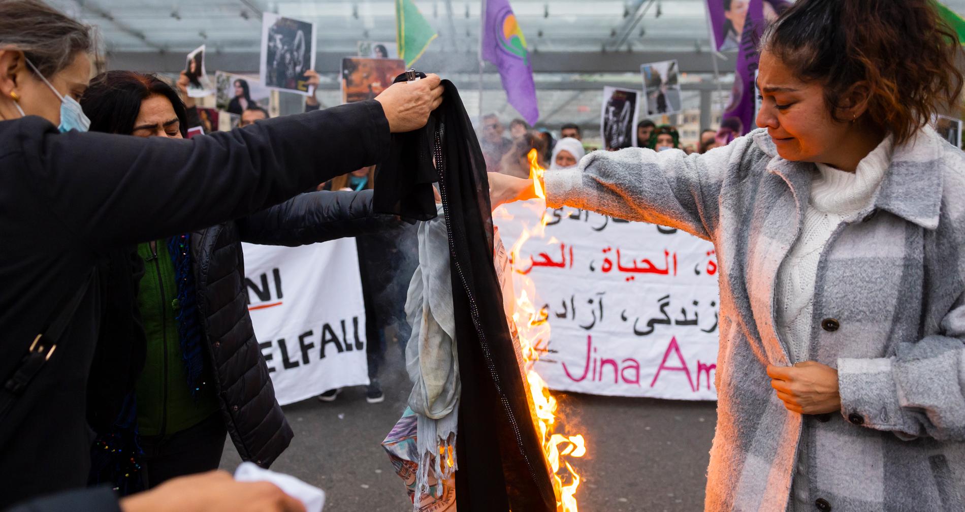 Bern, Schweiz. Kvinnor bränner sina huvudsjalar under en demonstration för kvinnors rättigheter i Iran. 