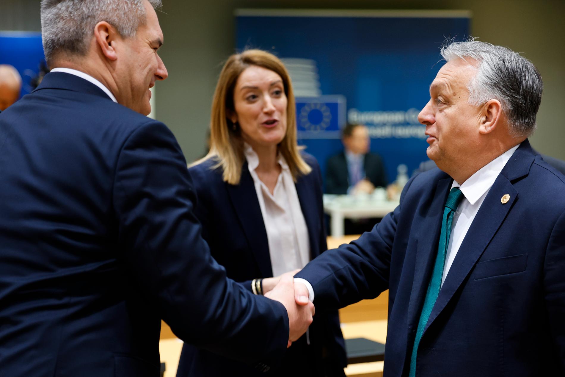 Ungerns premiärminister Viktor Orbán, till höger, skakar hand med Österrikes kansler Karl Nehammer efter beslutet. I mitten EU-parlamentets ordförande Roberta Metsola.