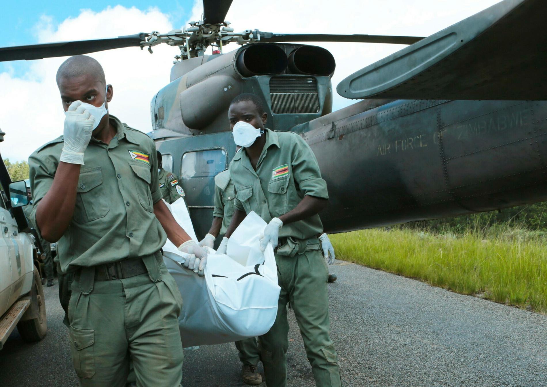 Personal lastar av en kropp från en militärhelikopter i Chimanimani,  600 km sydöst om Harare, Zimbabwe.