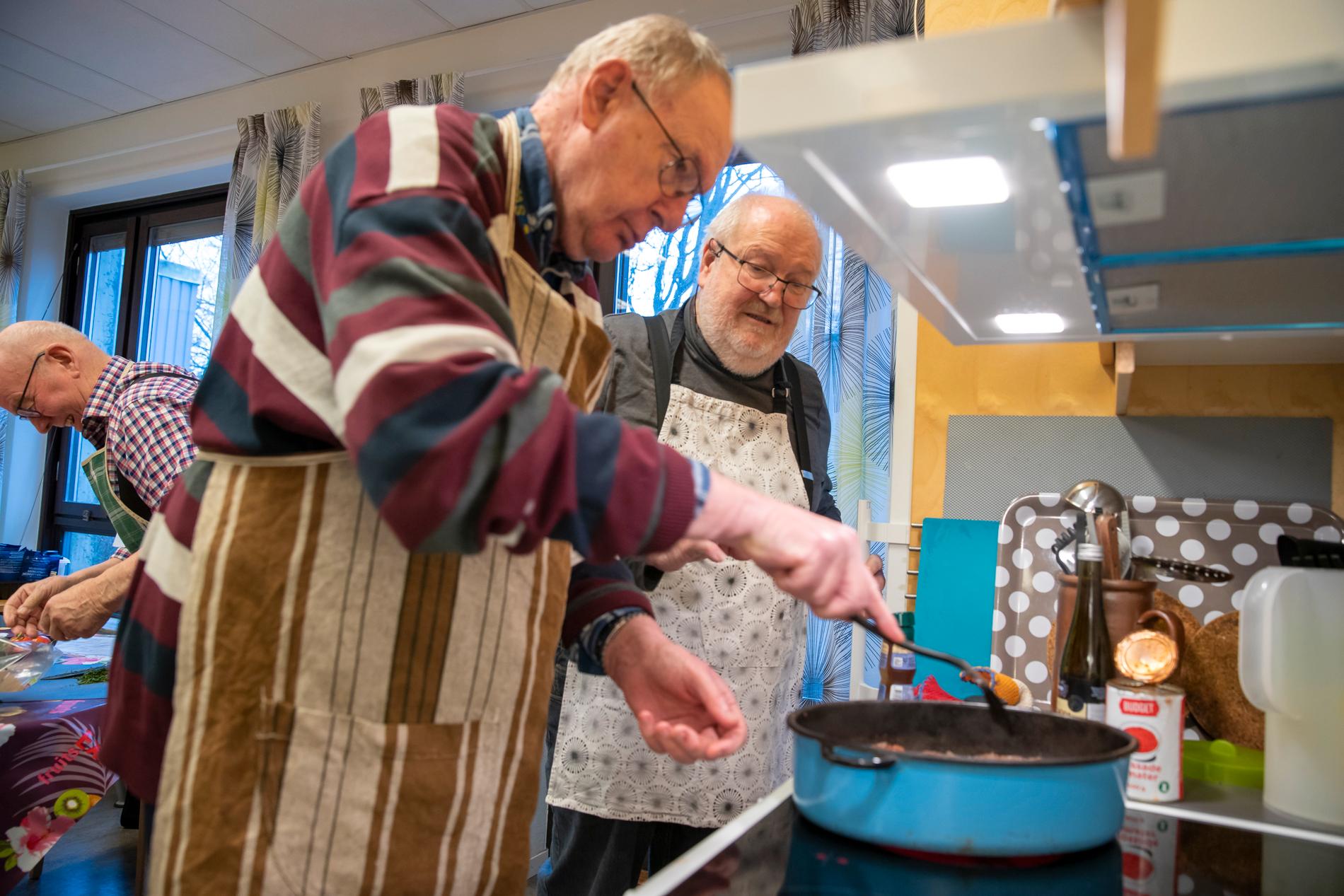 ”Efter elva år med matcirkeln finns det en uppsjö av  gubbar i Höganäs som har lärt sig att laga mat, den äldsta 97 år”, säger cirkelledaren Jan-Olov Skilberg. Här hjälper han en av deltagarna i matlaget att få till rätt stekyta på den dovhjort som utgör basen i dagens viltgryta.