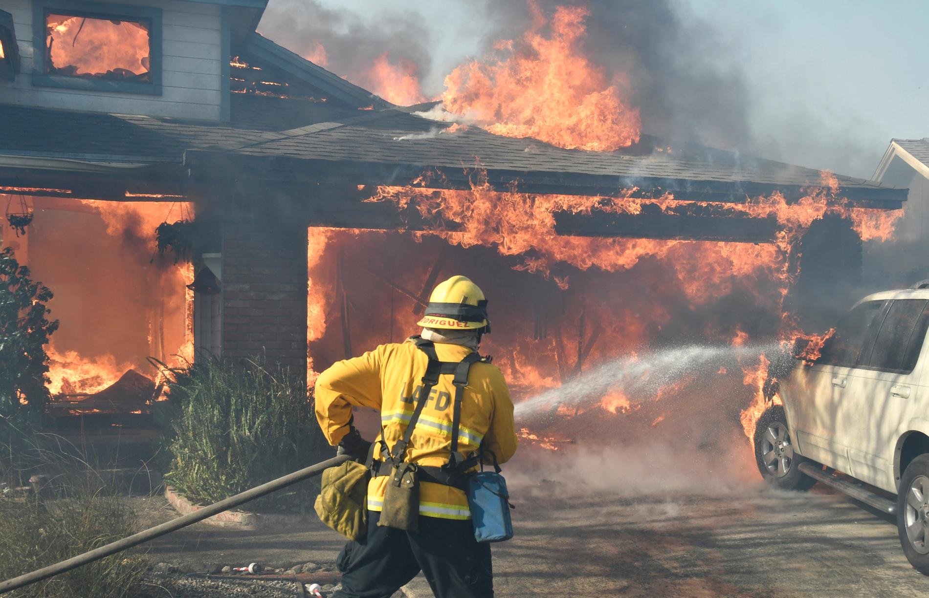 Brandman bekämpar brinnande hus i Kagel Canyon.