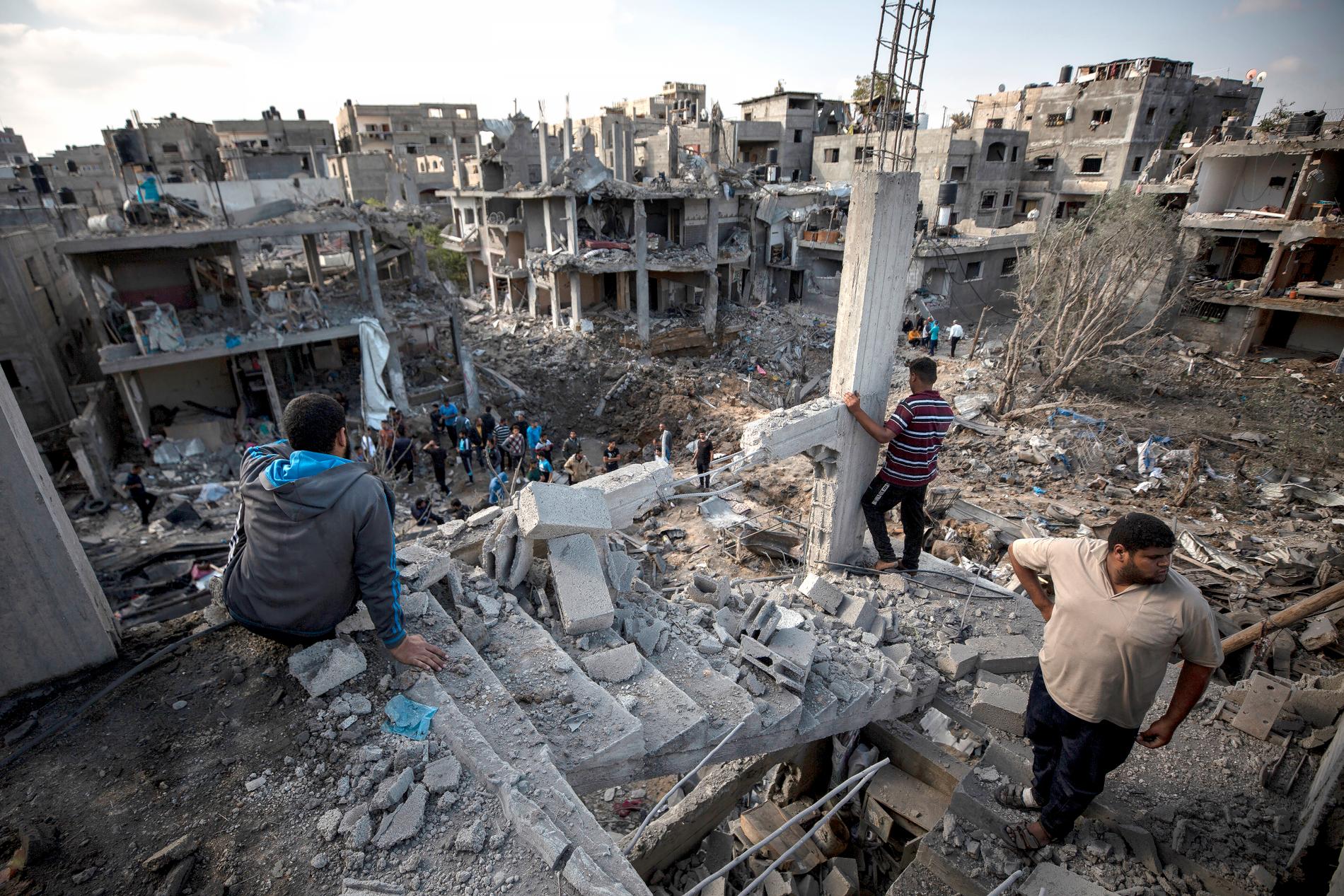 Palestinier vid sina förstörda hus i Beit Hanoun, norra Gaza efter israeliska attacker natten mot fredag. 