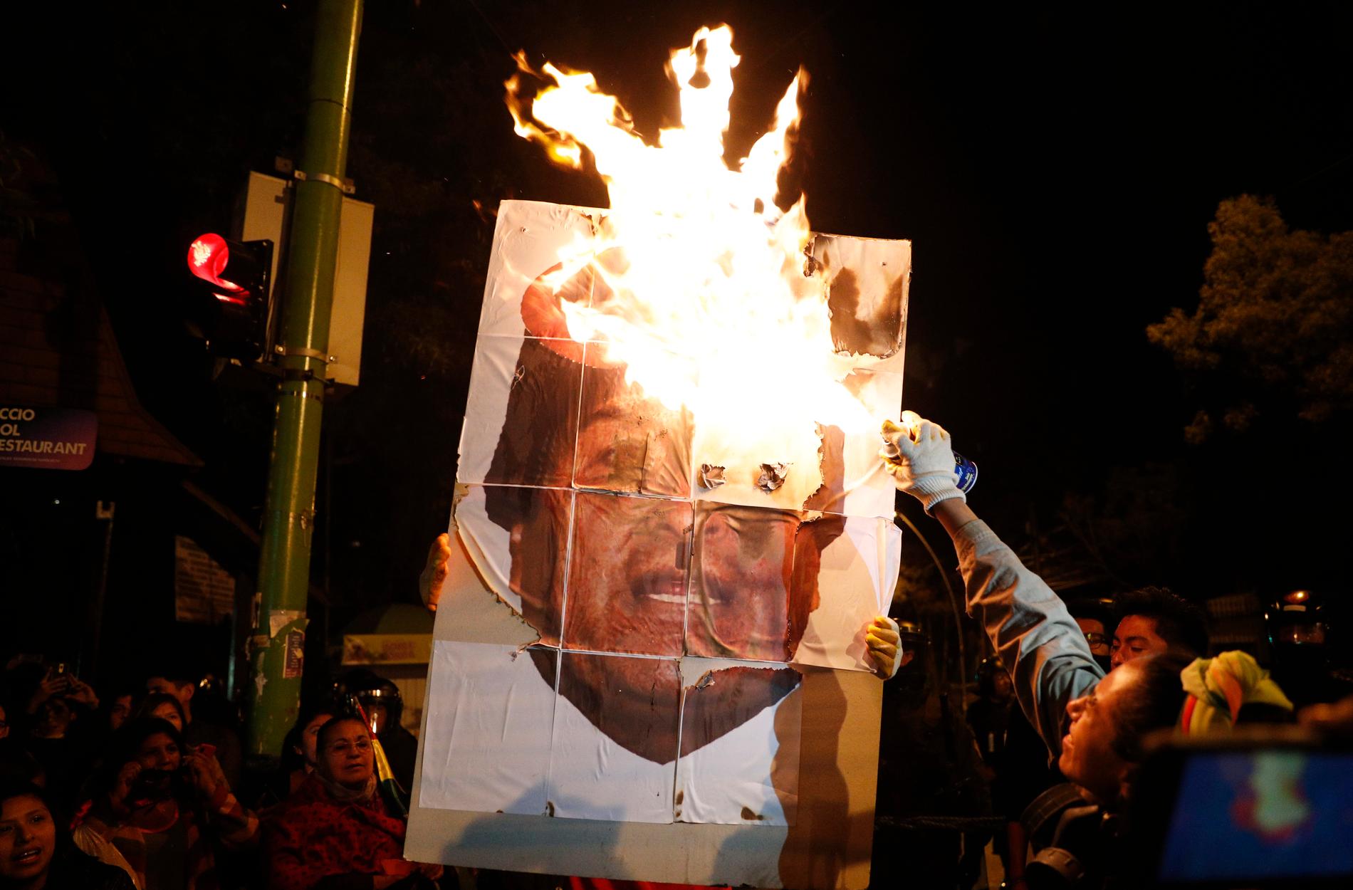 Demonstranter bränner en bild av president Evo Morales i Bolivias huvudstad La Paz den 26 oktober.