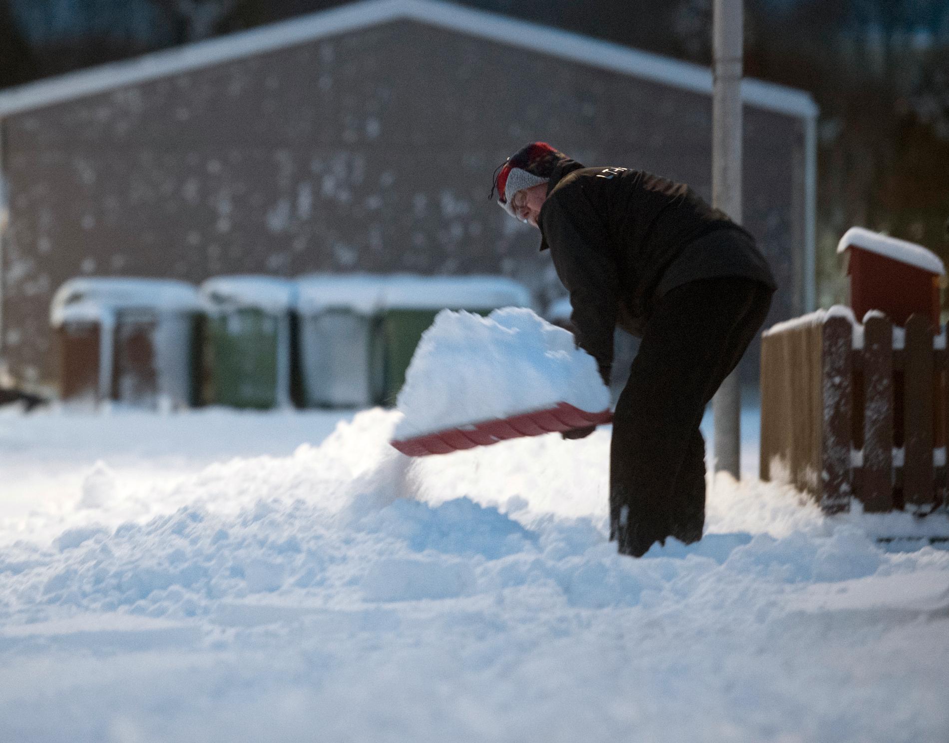 En mann skottar snö i Enköping.