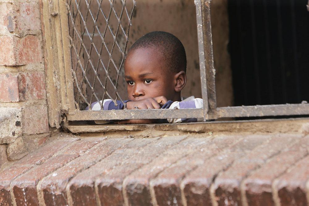 Ett litet barn tittar ut i ett nerstängt Harare, Zimbabwe, där bristerna inom vården är stora.