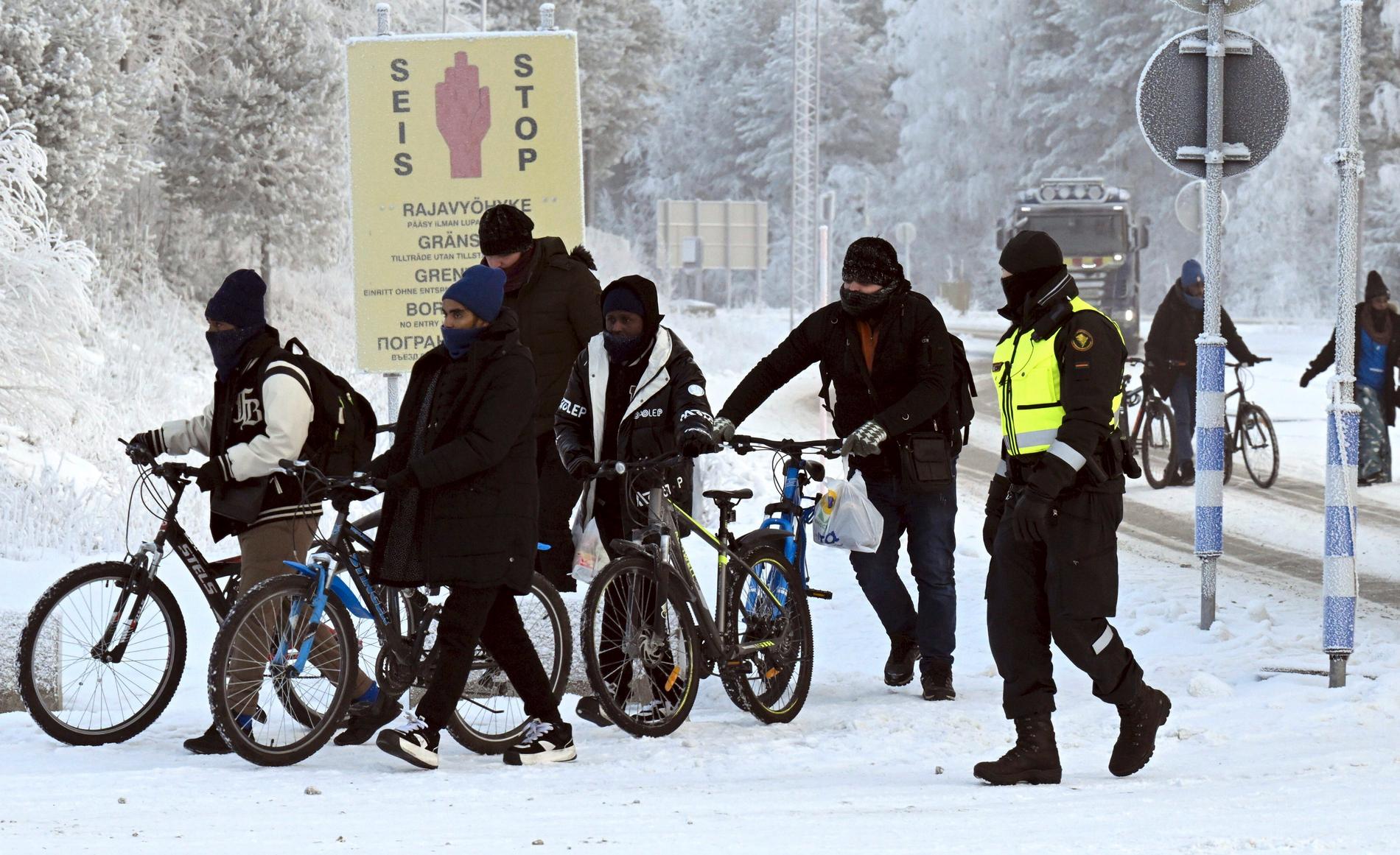 En gränsvakt vid Salla i norra Finland eskorterar flyktingar nyss anlända på cykel.