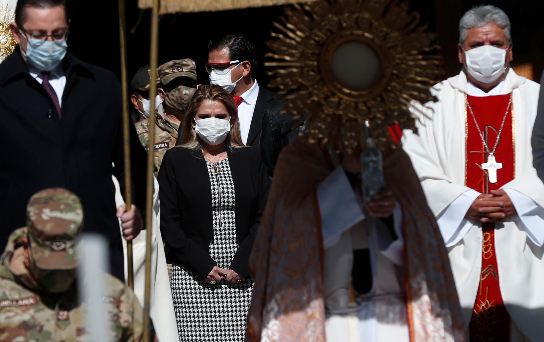 Bolivias interrimspresident Jeanine Áñez, i munskydd till vänster, vid ett sällsynt offentligt framträdande under en religiös högtid i juni.