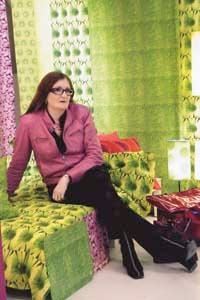 Carina Hägg är textildesigner och känd för sina färgsprakande fototryck med blommor, bambu, krokodilskinn och hjärtan. Här omgiven av sin egen gröna mönsterdjungel.