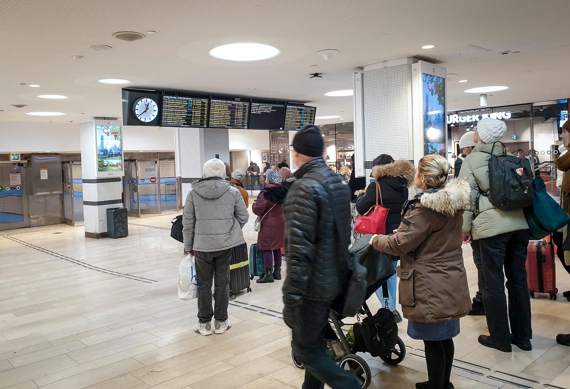 Resenärer tittar på avgångstavlorna på Stockholms central den 28 november, då tåg försenades på grund av kraftigt snöfall. Arkivbild.