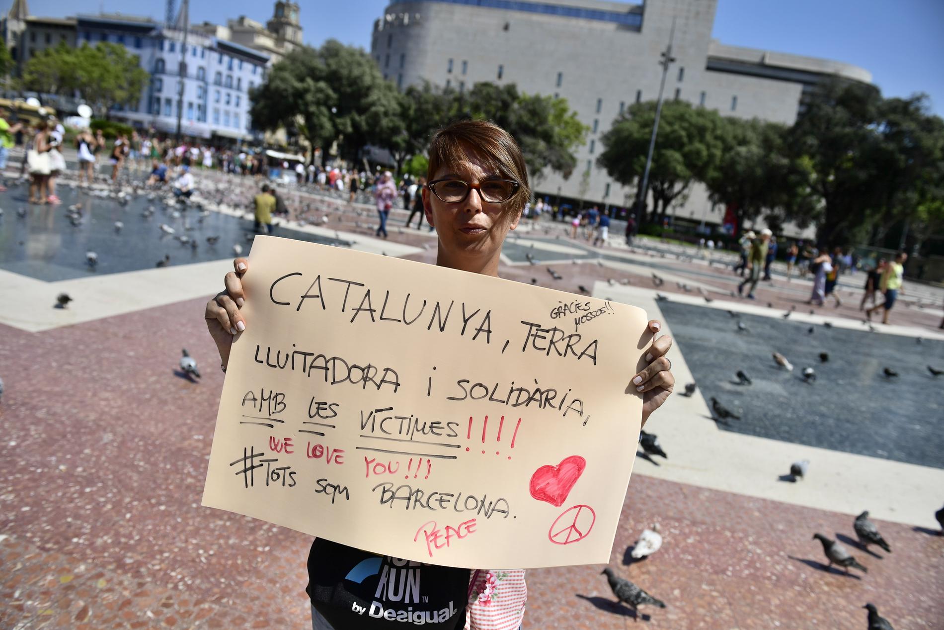 Cristina Galdames, 39, håller upp en skylt som det står ”Katalonien står i solidaritet med offren. Vi älskar er” på.
