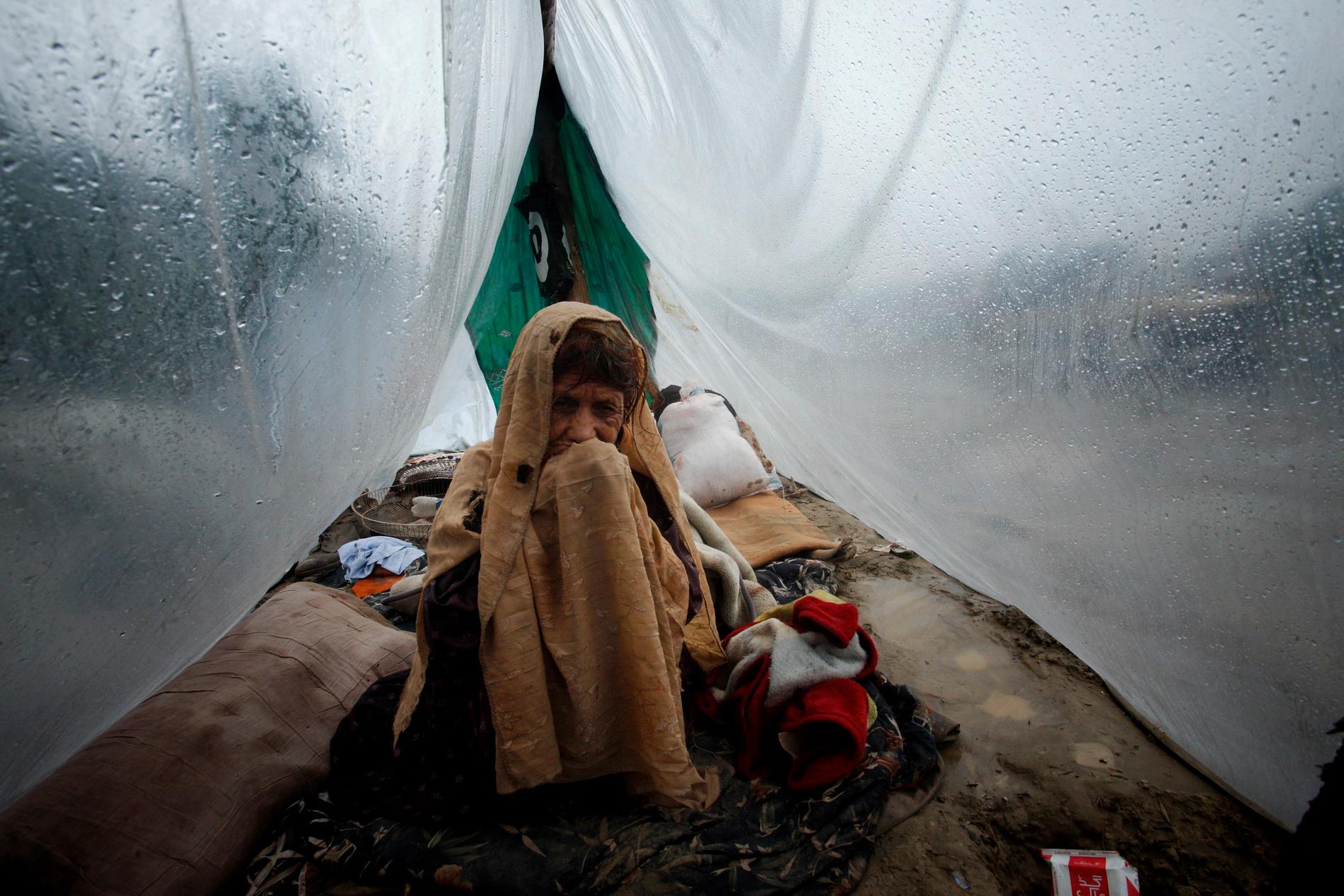 Pakistansk kvinna tar skydd från kraftigt regn i närheten av Pabbi. 