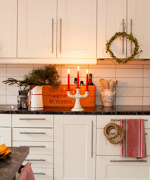 Den trearmade ljusstaken är vintage och ingår i God jul-serien från Gustavsberg. Kransen har Martina tillverkat av en gammal kemtvättsgalge och buxbom från trädgården. Köket är egenritat och har luckor från Ikea.
