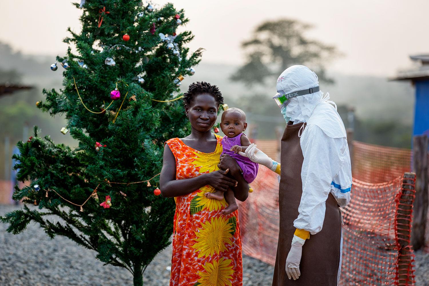 VÅRDAR SIN DOTTER Det står en smyckad julgran i den röda sanden på gården utanför tältet där de ebolasjuka vårdas. Där står Korto, mamma till tre månader gamla Josephine, som smittats av ebola. Korto har själv överlevt sjukdomen och är nu immun och tar därför hand om sin dotter på kliniken.