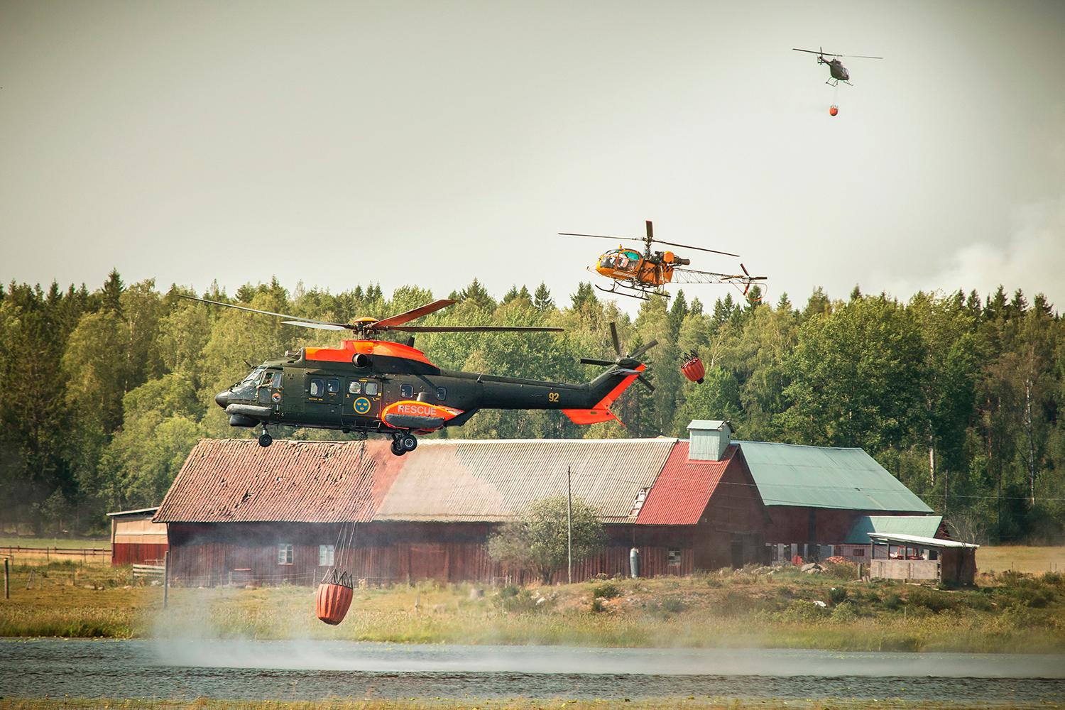 Helikoptrar hämtar vatten för att bekämpa branden i Sala.