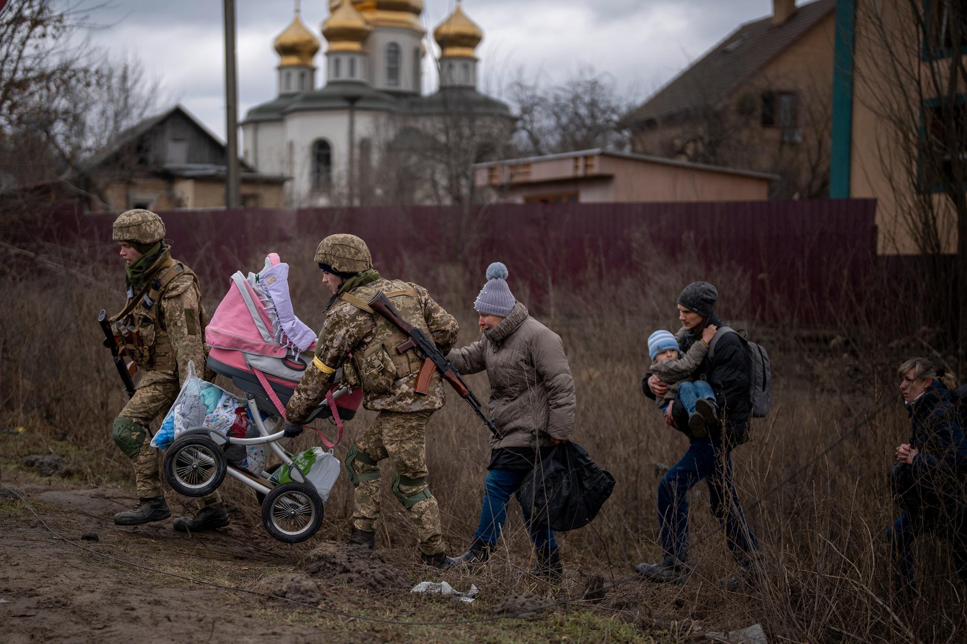 Ukrainska soldater hjälper en familj att fly i utkanten av Kiev. 